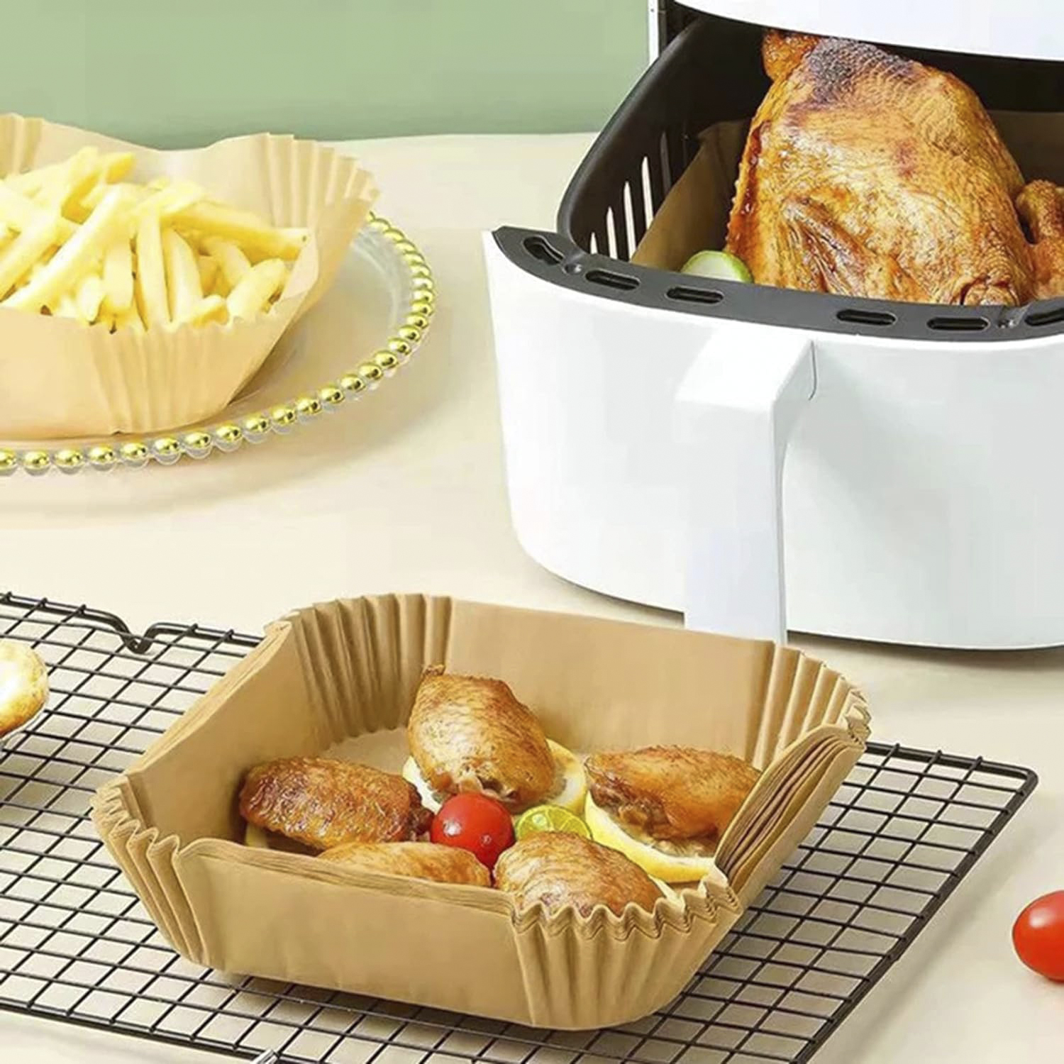 Comida en papel pergamino en una bandeja. Papas fritas, alitas y pollo asado en una freidora de aire.