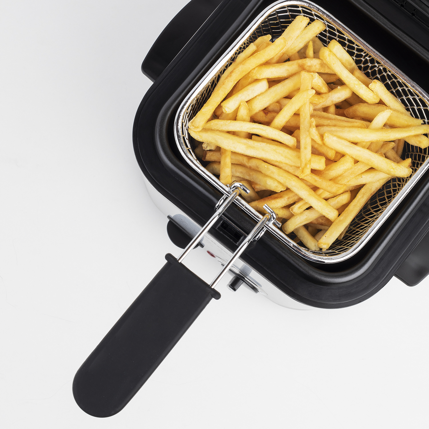 Frittierkorb mit goldenen Pommes Frites gefüllt, ruht im Frittiergerät.