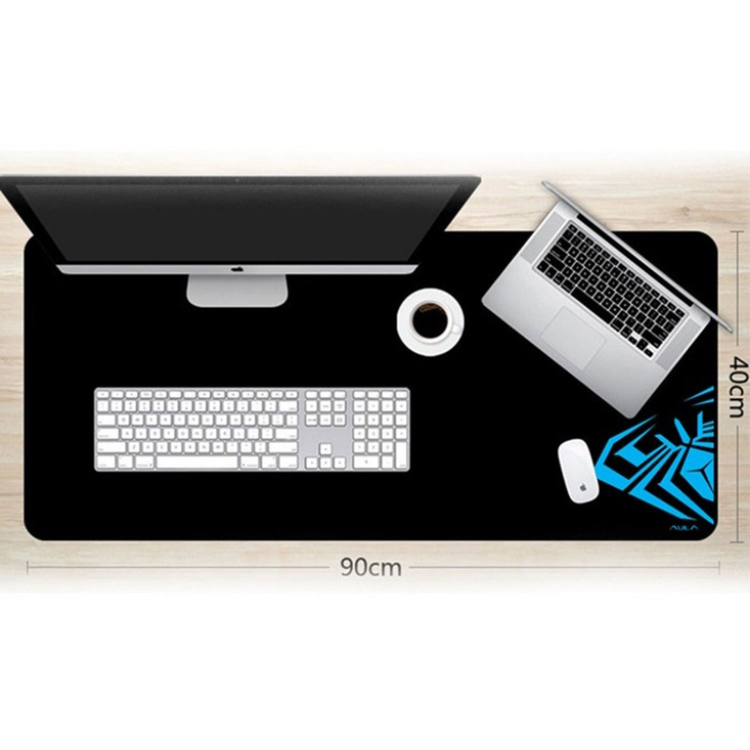 Una configuración de escritorio con un monitor, portátil, teclado, ratón y una taza en una alfombrilla negra.