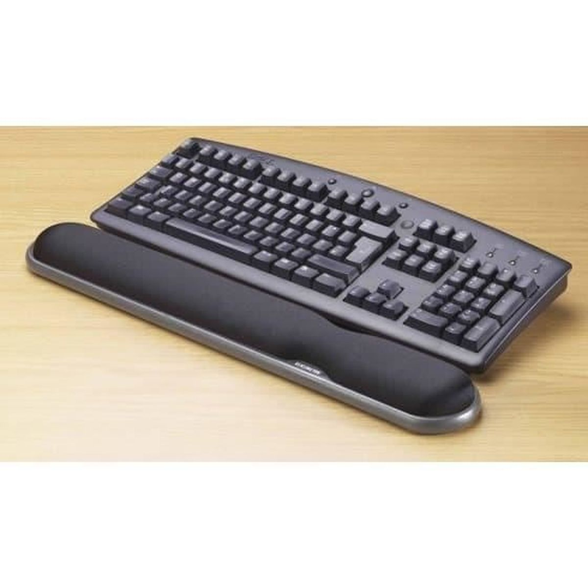 Un teclado con reposamuñecas sobre una superficie de madera. Es un teclado ergonómico negro.