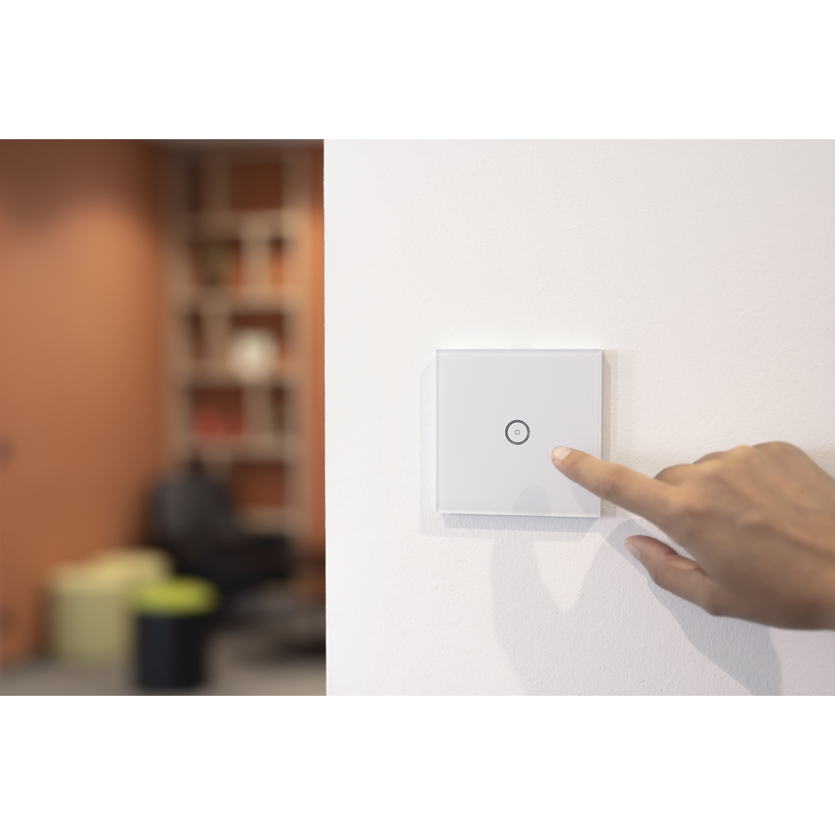 Ein Finger berührt einen weißen Lichtschalter an einer weißen Wand, mit unscharfem Hintergrund.