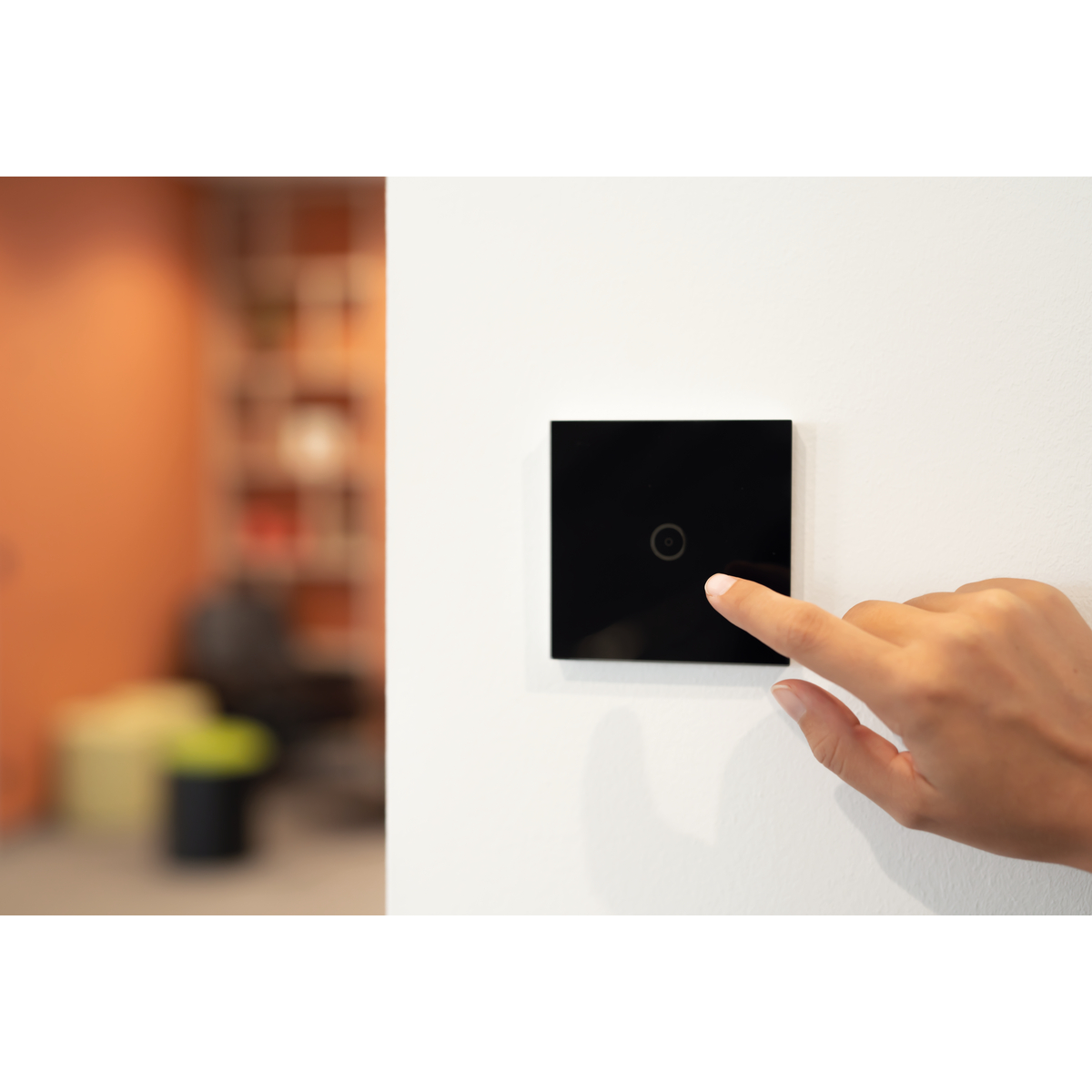 Ein schwarzer Lichtschalter an einer weißen Wand, mit einem Finger, der den mittleren Knopf drückt.