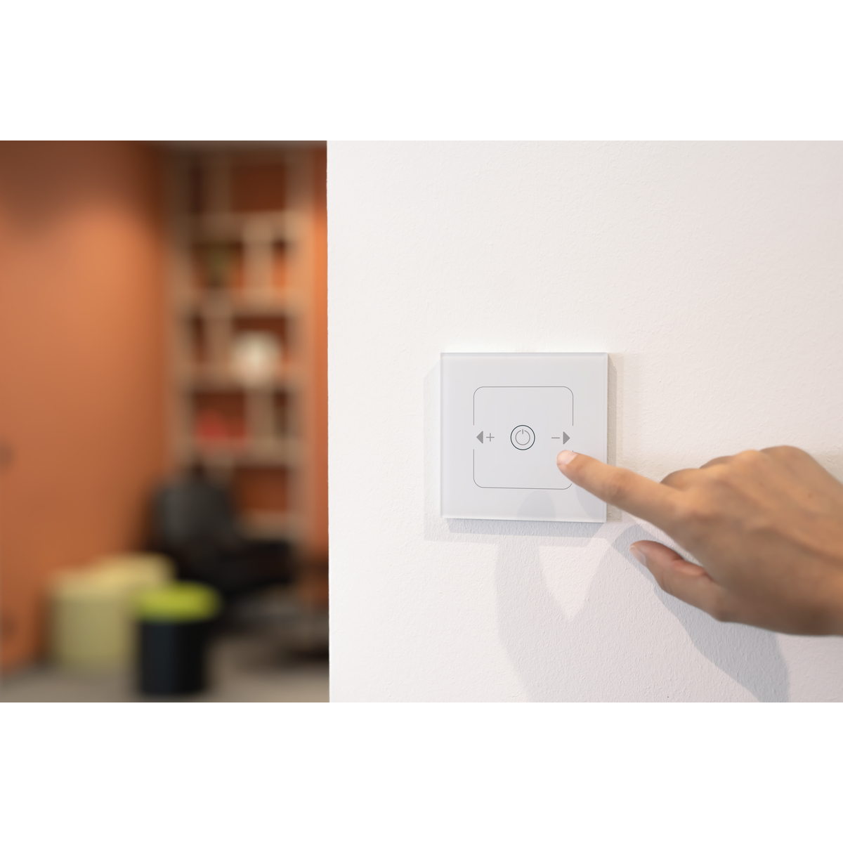 Lichtschalter mit Plus- und Minuszeichen, Finger berührt das Minuszeichen, verschwommener Hintergrund.