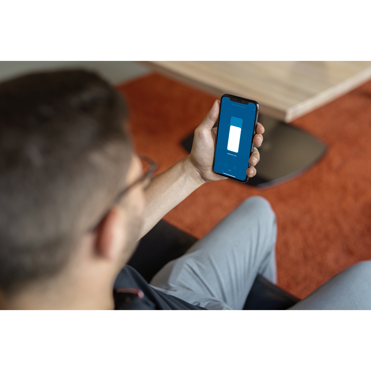 Mann, der ein Telefon hält, das ein weißes Rechteck auf blauem Bildschirm zeigt.