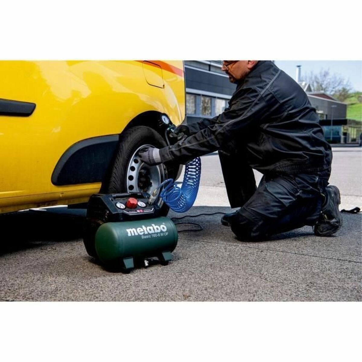 Mann kniet, pumpt einen Reifen mit einem grünen Luftkompressor auf, gelber Autohintergrund.