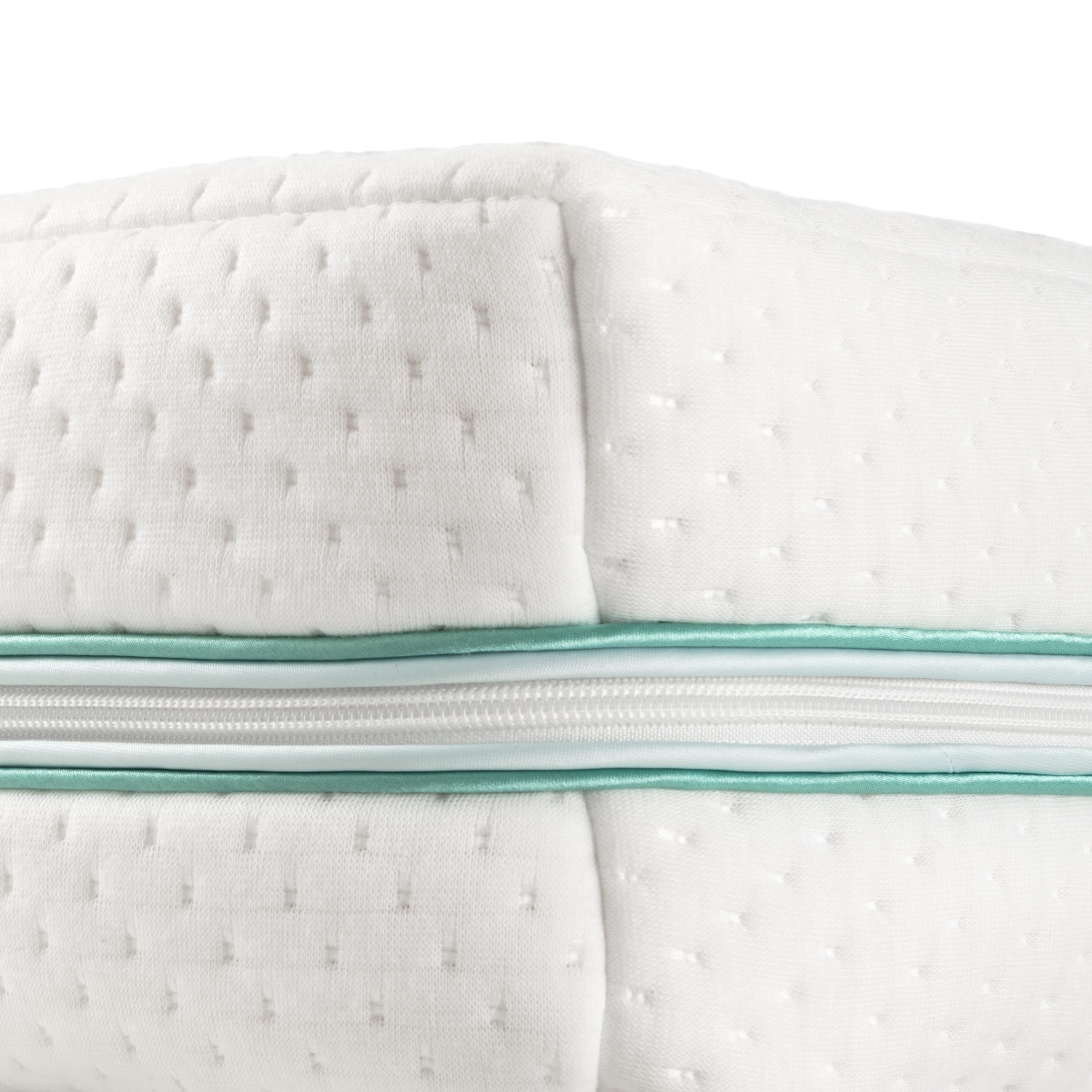 Primer plano de almohada blanca con cremallera, superficie texturizada y borde turquesa.