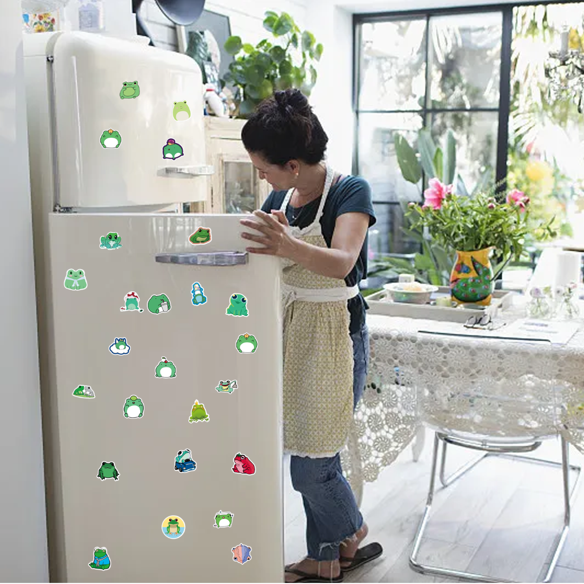 Eine Frau klebt Froschaufkleber auf einen weißen Kühlschrank. Es gibt verschiedene Froschaufkleber.
