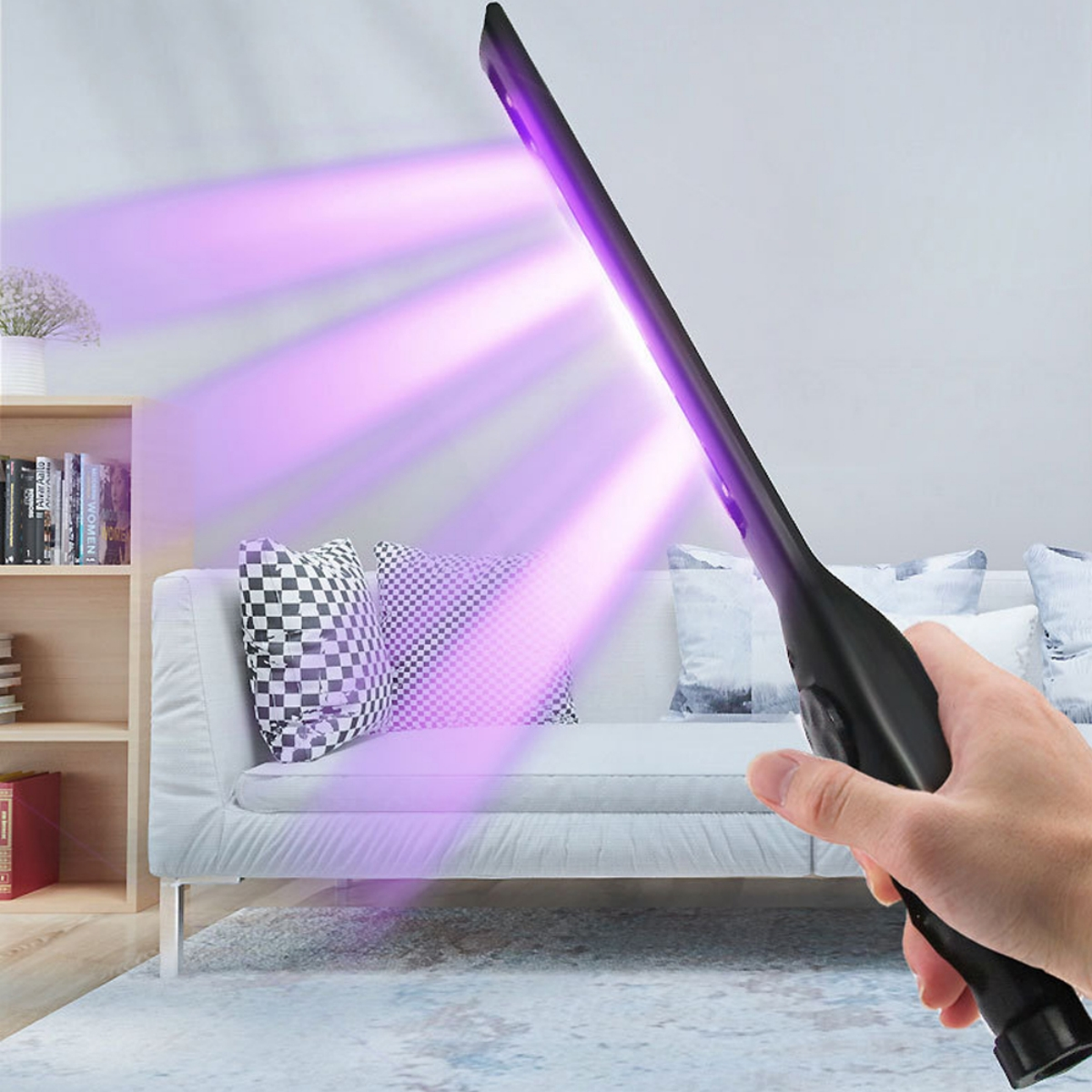 Hand hält UV-Stablampe, die violettes Licht auf ein Sofa projiziert.