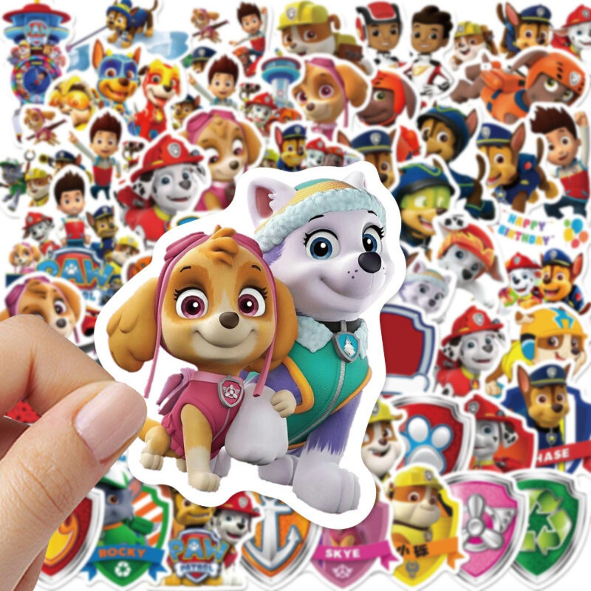 Hand hält Aufkleber von Paw Patrol-Figuren, Skye und anderen Zeichentrickhunden.