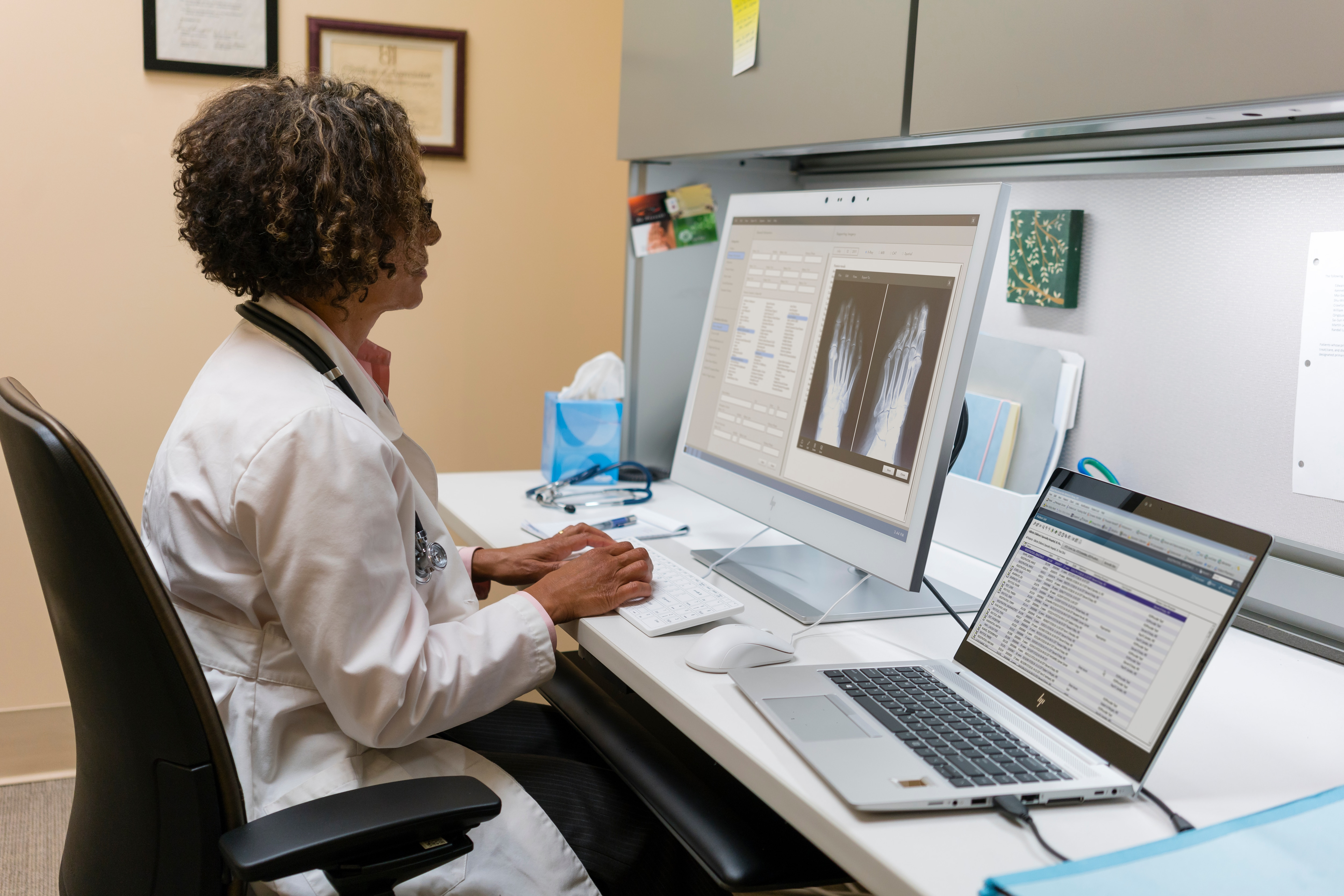 Un medico che lavora a una scrivania con un computer e un laptop.