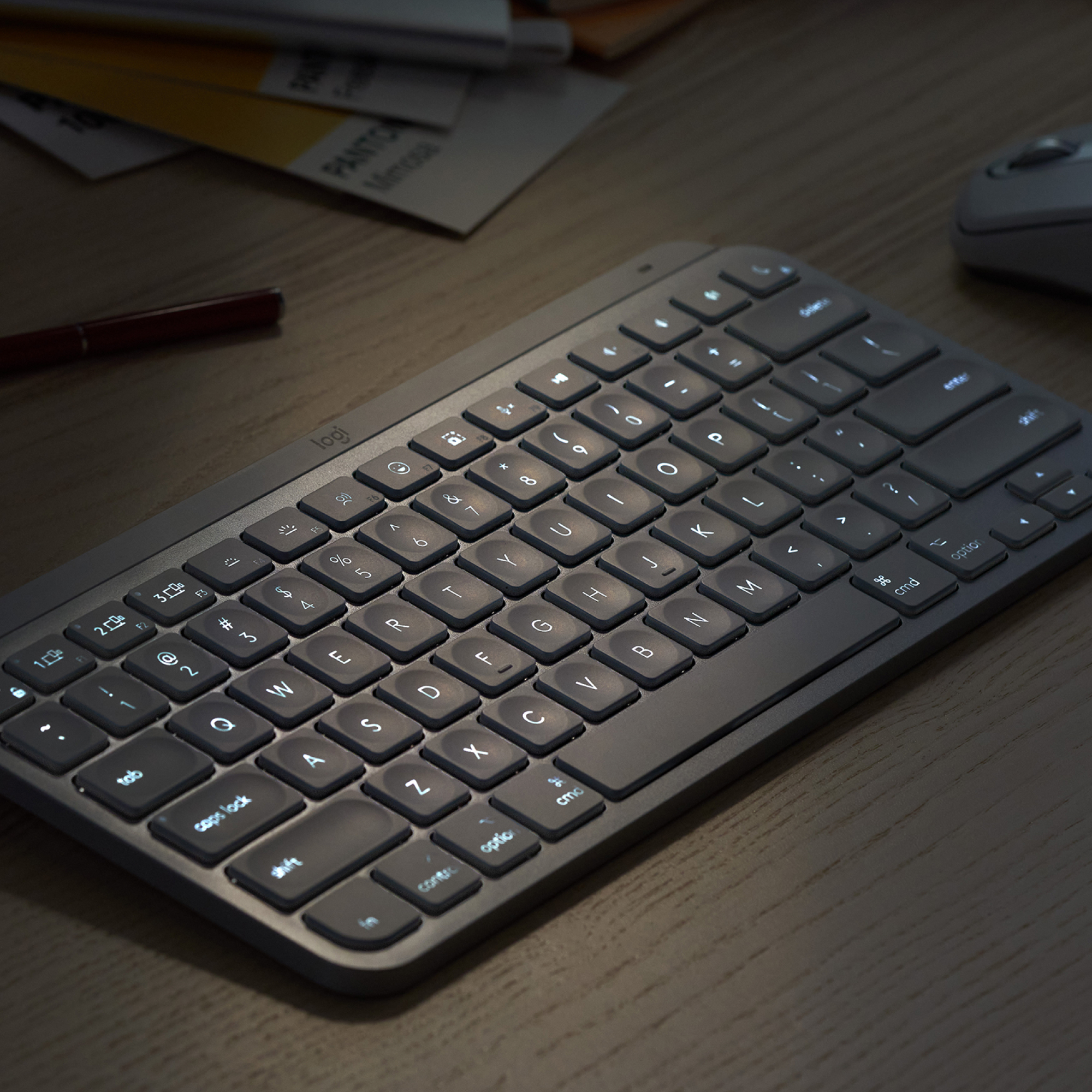 A silver keyboard with backlit keys on a desk.