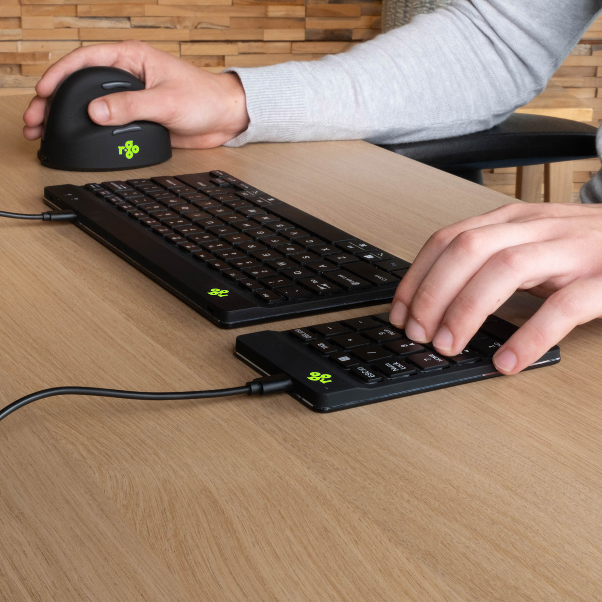 Eine schwarze Tastatur und ein Nummernblock, verbunden mit einer schwarzen Maus. Alles auf einem Holztisch.