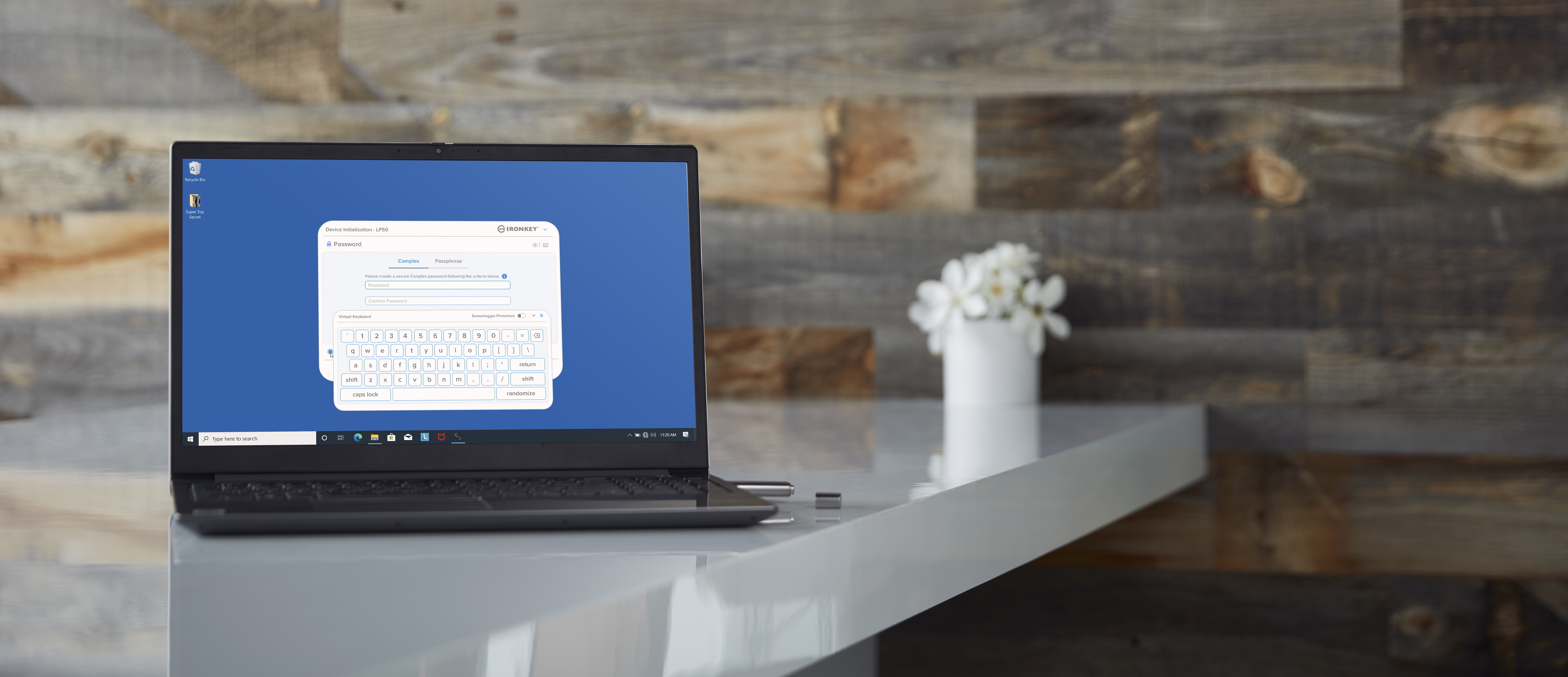 Laptop su una scrivania bianca mostra una schermata di accesso. Un vaso bianco con fiori è accanto.