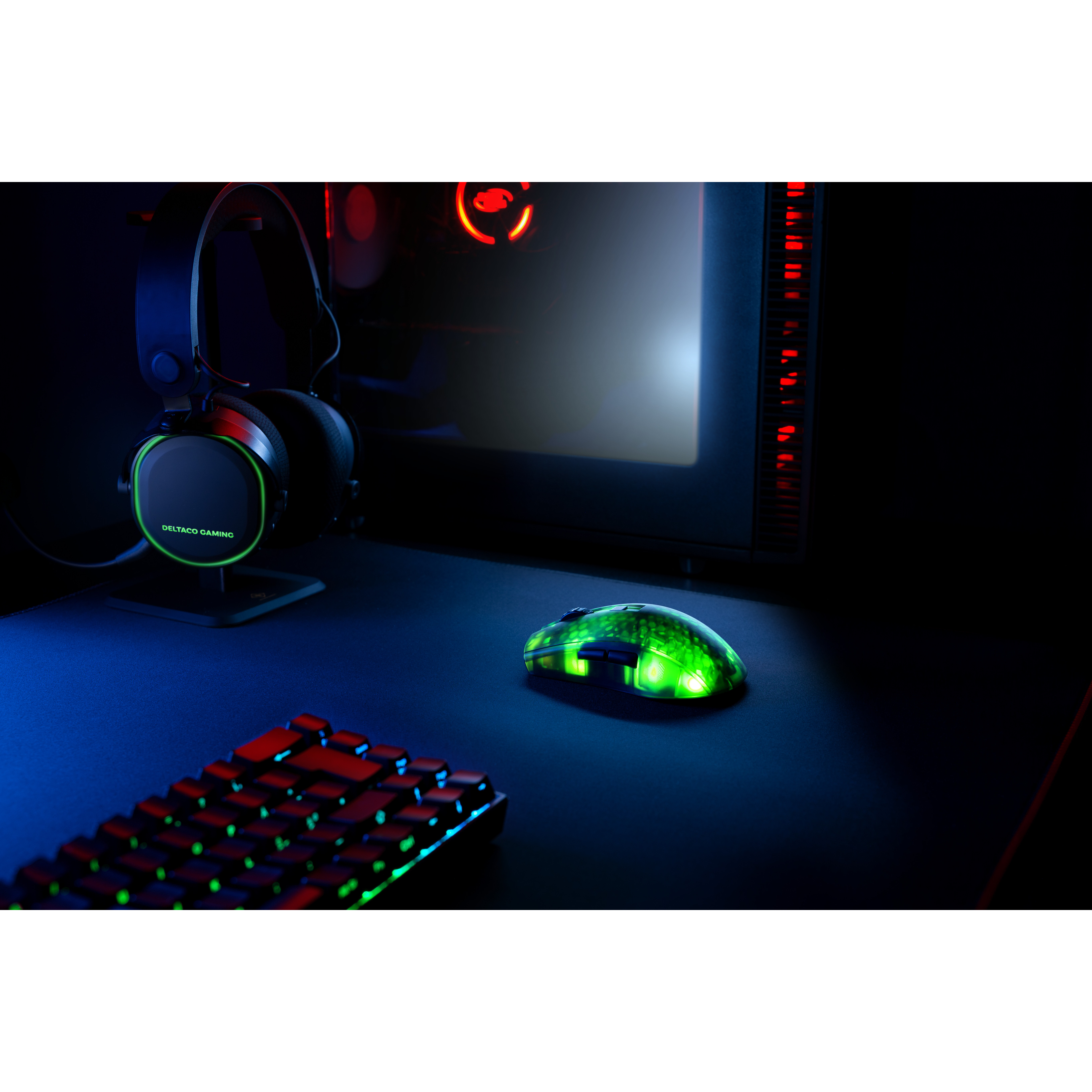 Gaming-Setup mit einer grün beleuchteten Maus, Tastatur, Kopfhörern und einem Computer-Tower auf einem dunklen Schreibtisch.