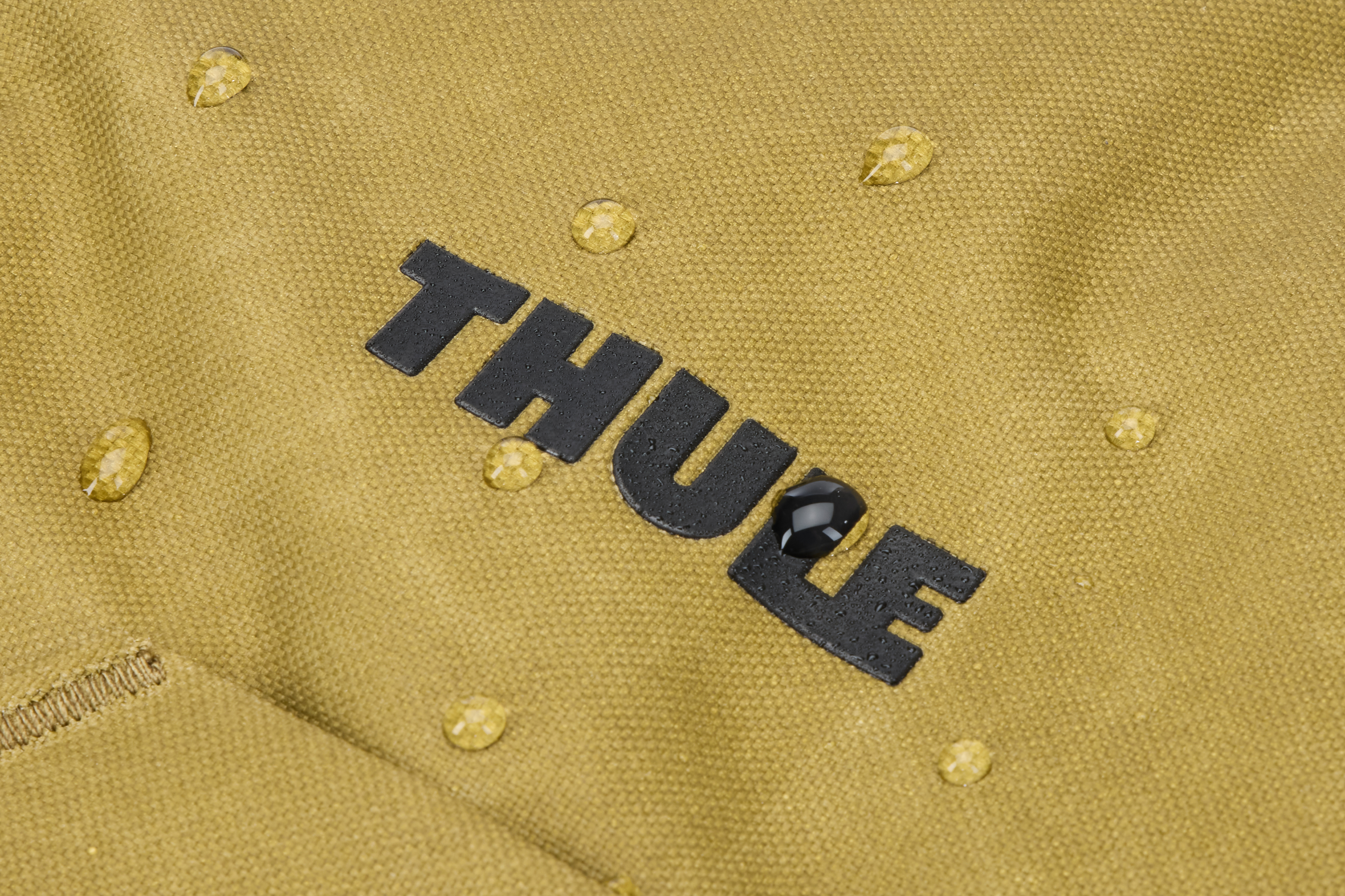 Logo Thule su un tessuto strutturato, con goccioline d'acqua. Il tessuto è beige.