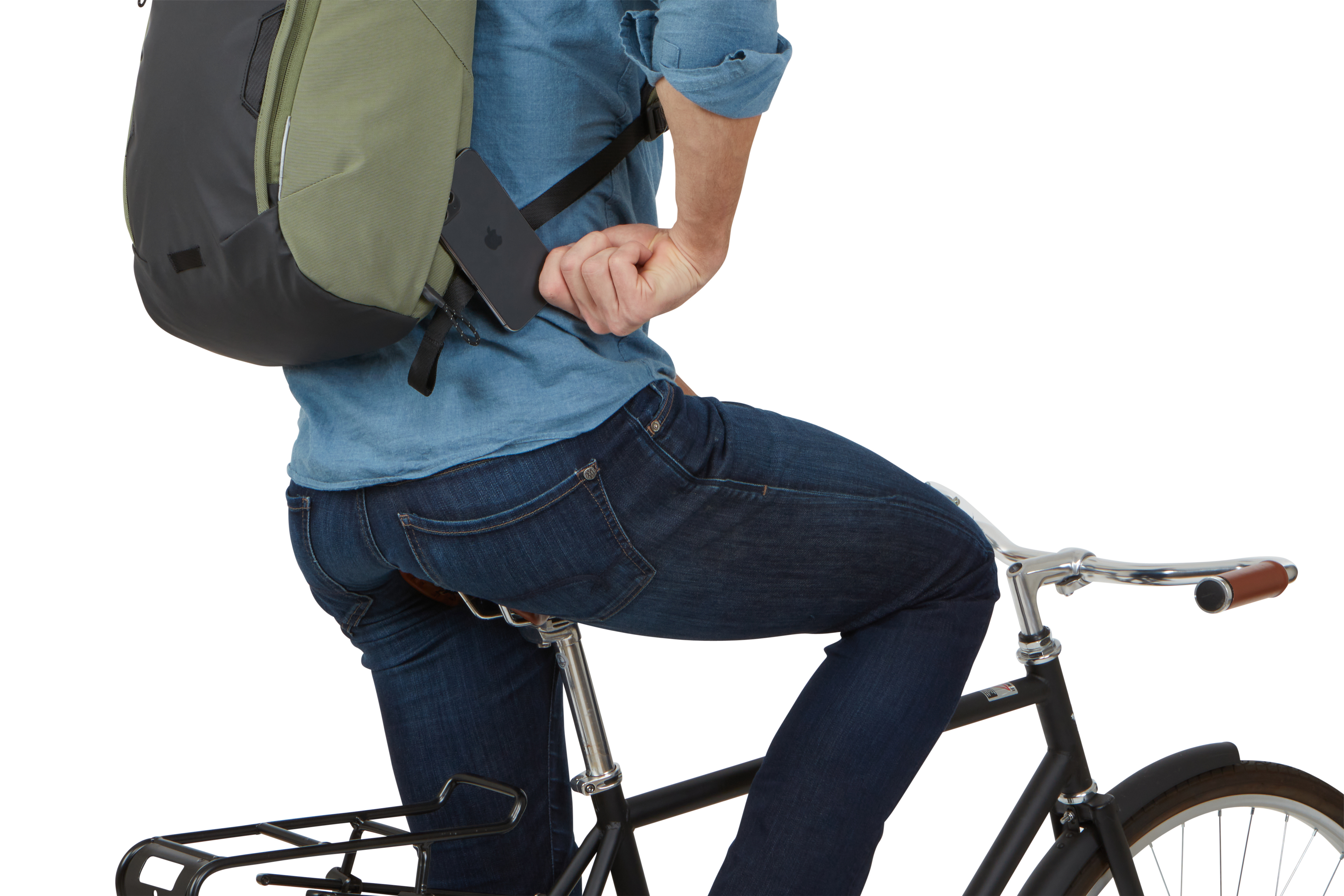 Person auf dem Fahrrad, die ein Telefon benutzt. Grüner und schwarzer Rucksack, Jeans, auf einem Fahrrad sitzend.