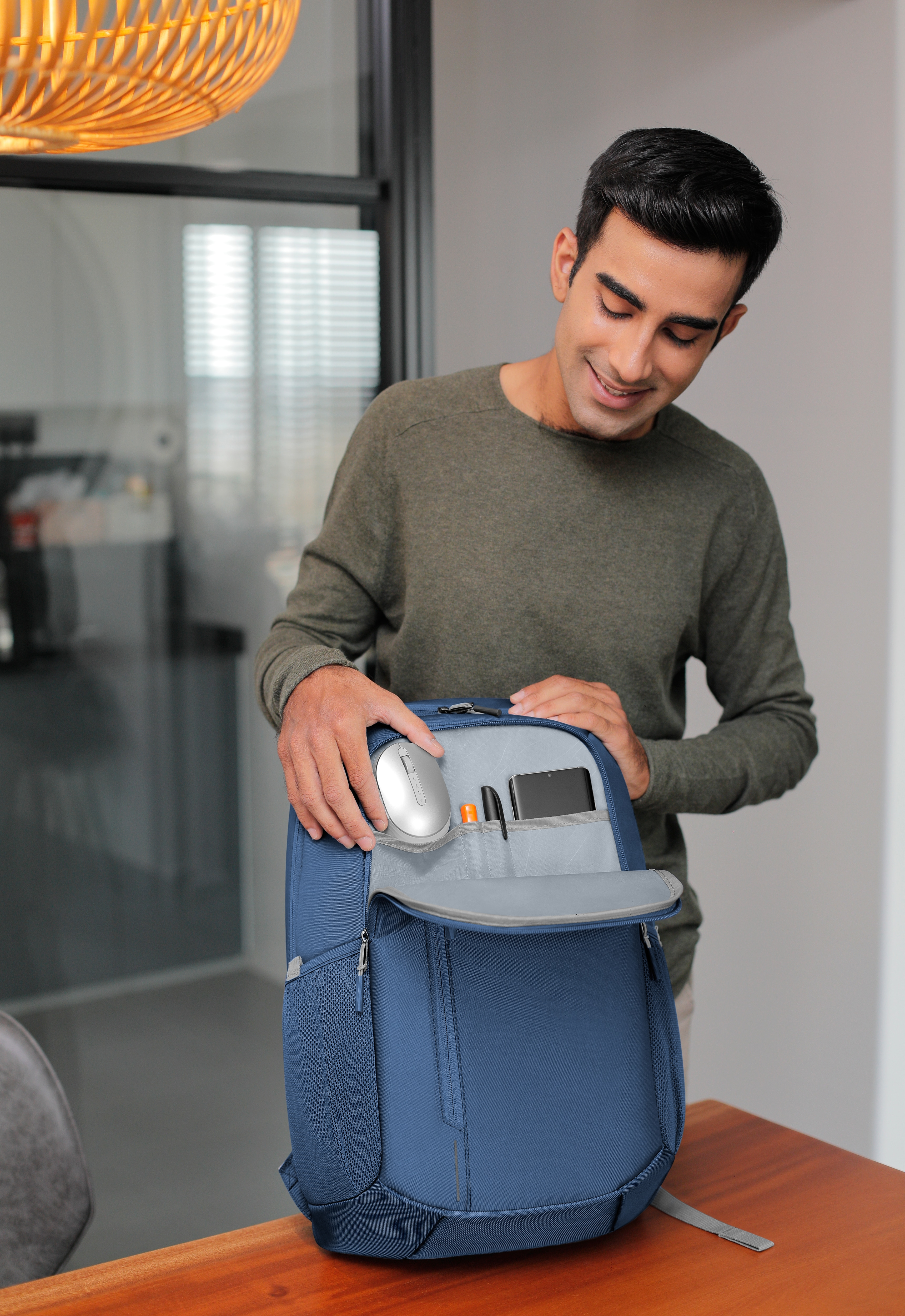 Mann öffnet einen blauen Rucksack und zeigt die darin enthaltenen Gegenstände.