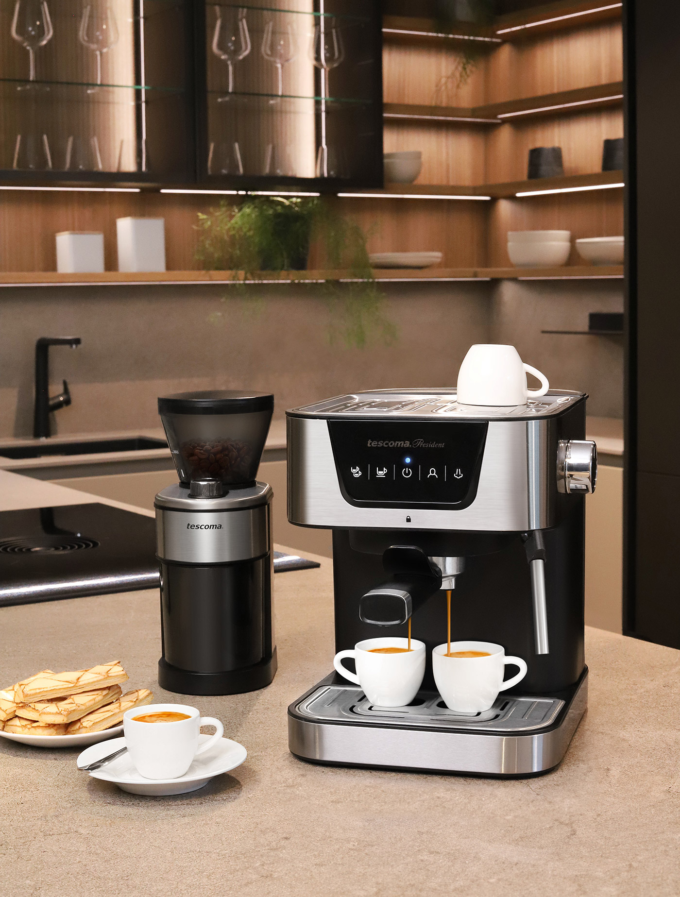 Espressomaschine mit zwei Tassen. Mühle daneben und ein Teller Kekse.