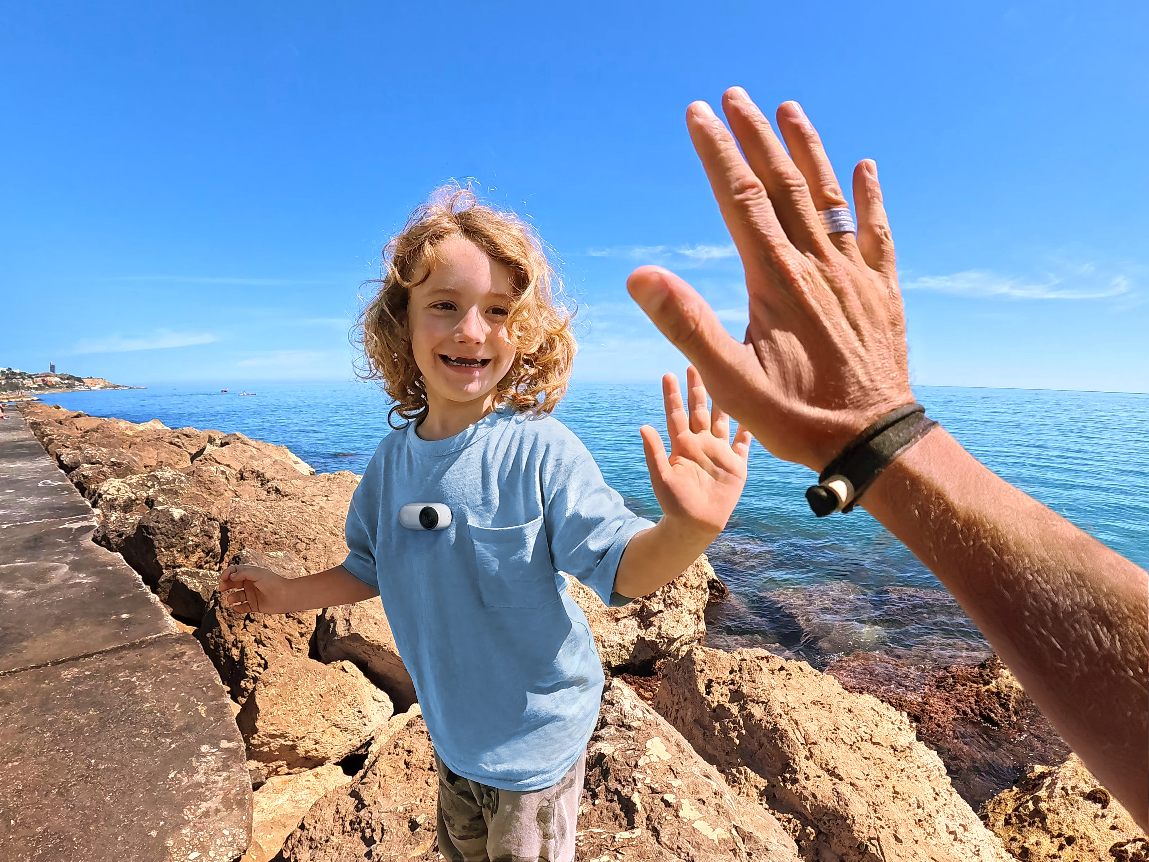 Chłopiec i mężczyzna dają sobie piątkę na molo. Błękitne niebo i morze w tle.