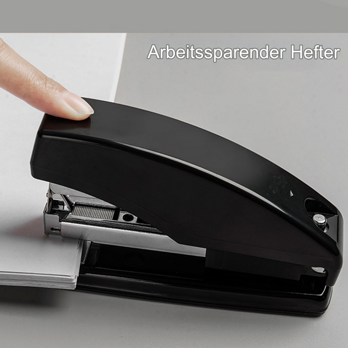 Eine Hand drückt auf einen schwarzen Tacker und heftet weiße Papiere auf einer grauen Oberfläche.