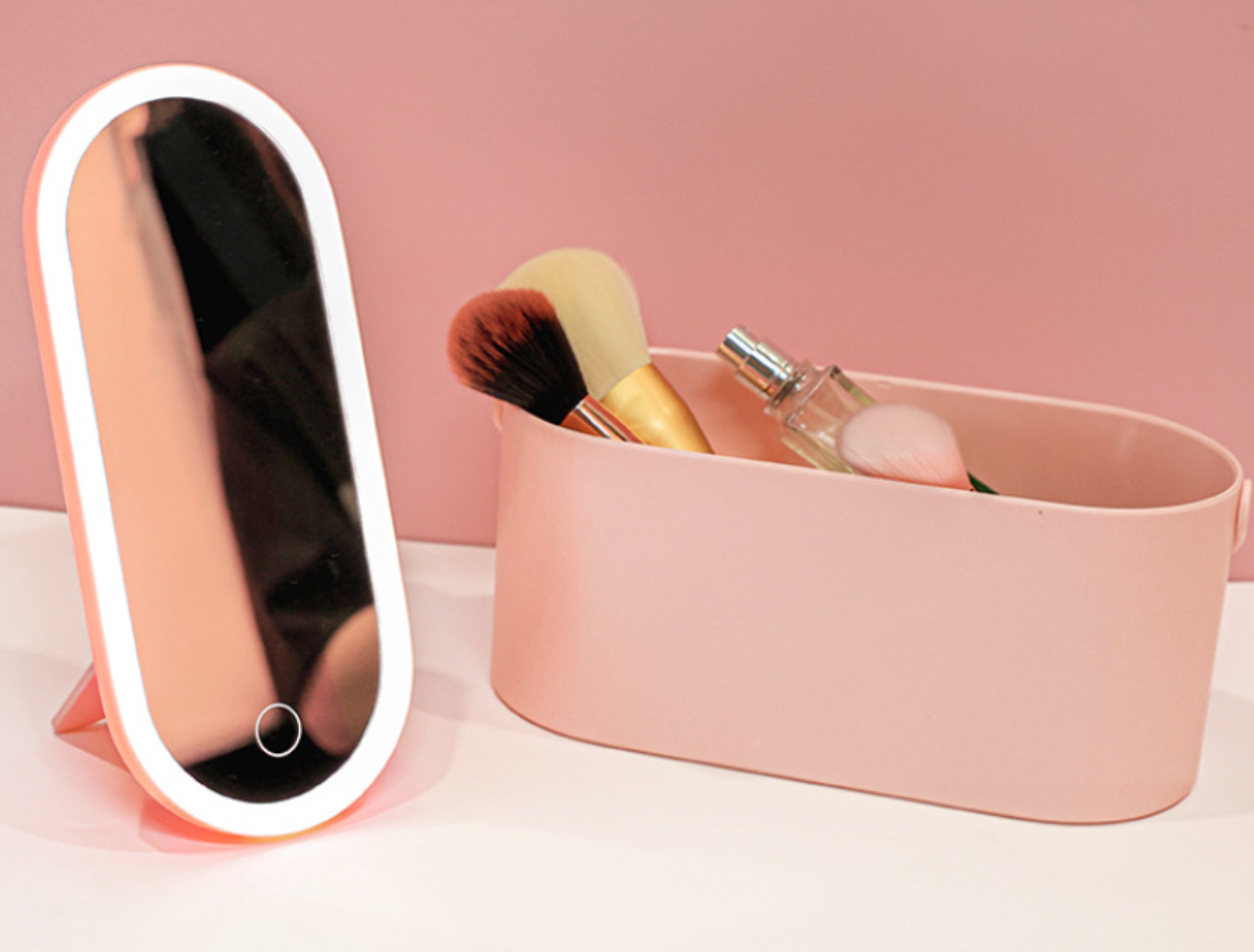 Ein rosa Make-up-Organizer mit Spiegel, Make-up-Pinseln und einer Parfümflasche.