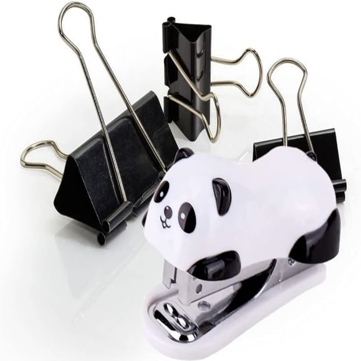 Tacker in Form eines Pandas neben drei schwarzen Büroklammern.