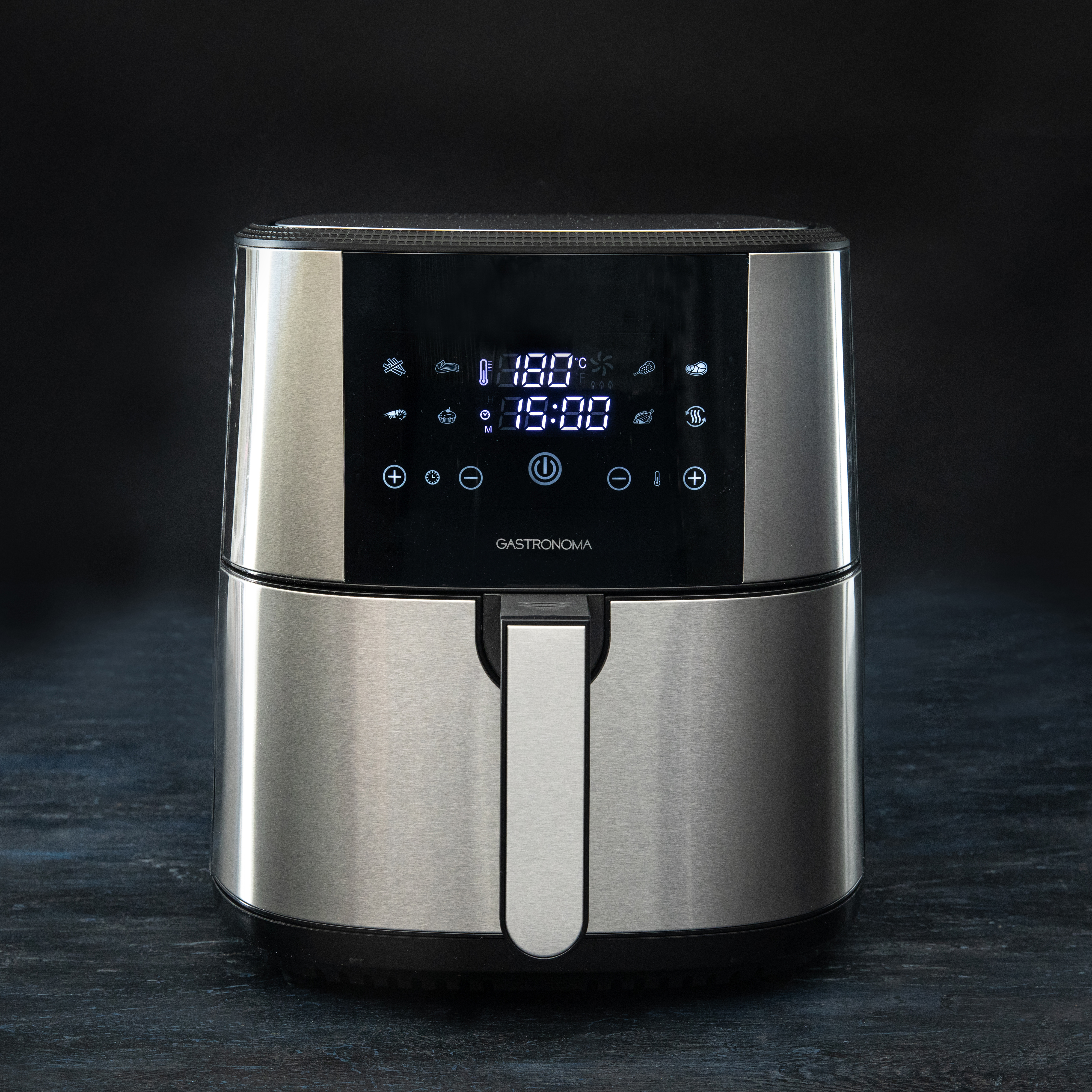 Silver and black air fryer. Digital display shows temperature and time. Dark background.