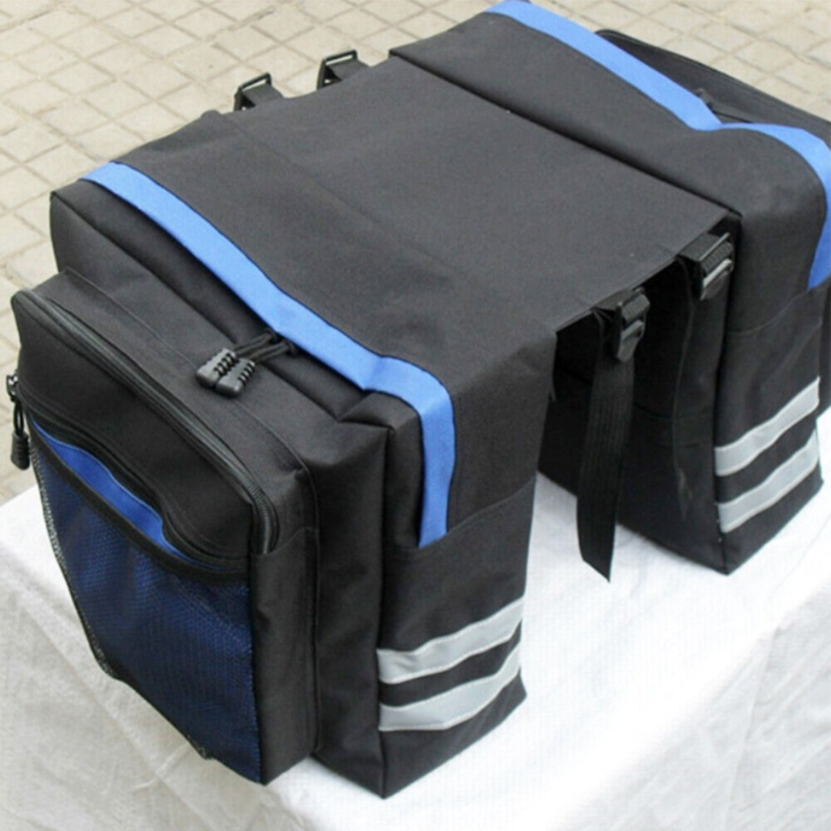 Schwarze Fahrradtaschen mit blauen Akzenten. Reflektierende Streifen an den Seiten.