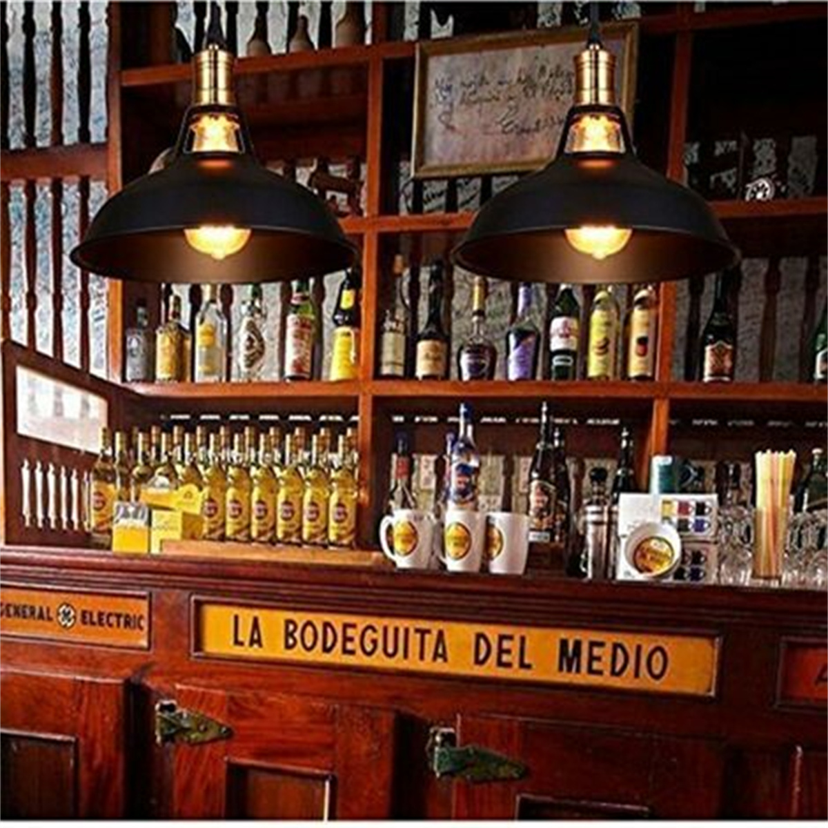 Bar-Innenraum mit hängenden schwarzen Lampen, Flaschen und einem Schild mit der Aufschrift 'La Bodeguita del Medio'.