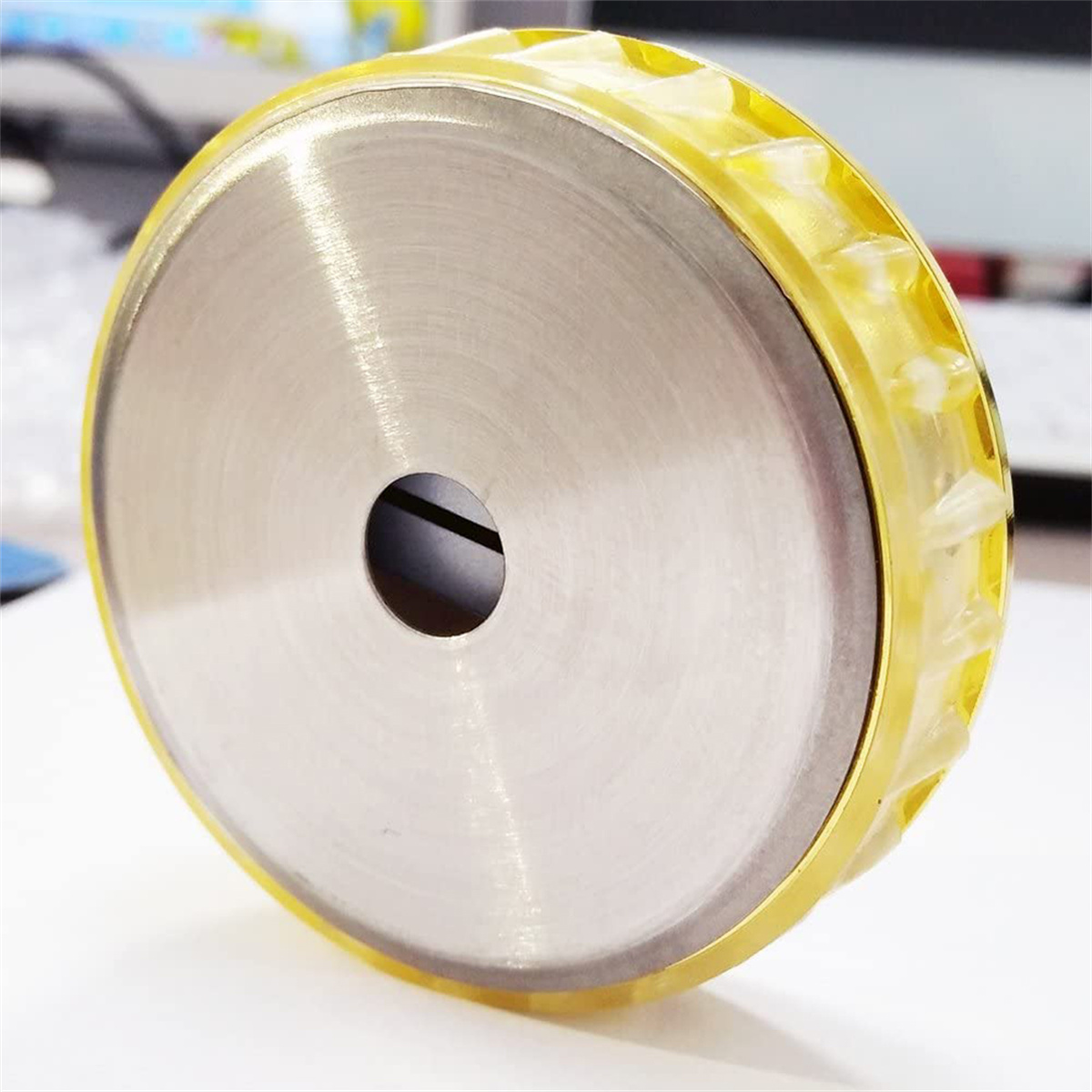 Silberne und gelbe Metallscheibe. Glänzende Oberfläche mit Loch in der Mitte. Gelber, geriffelter Rand.