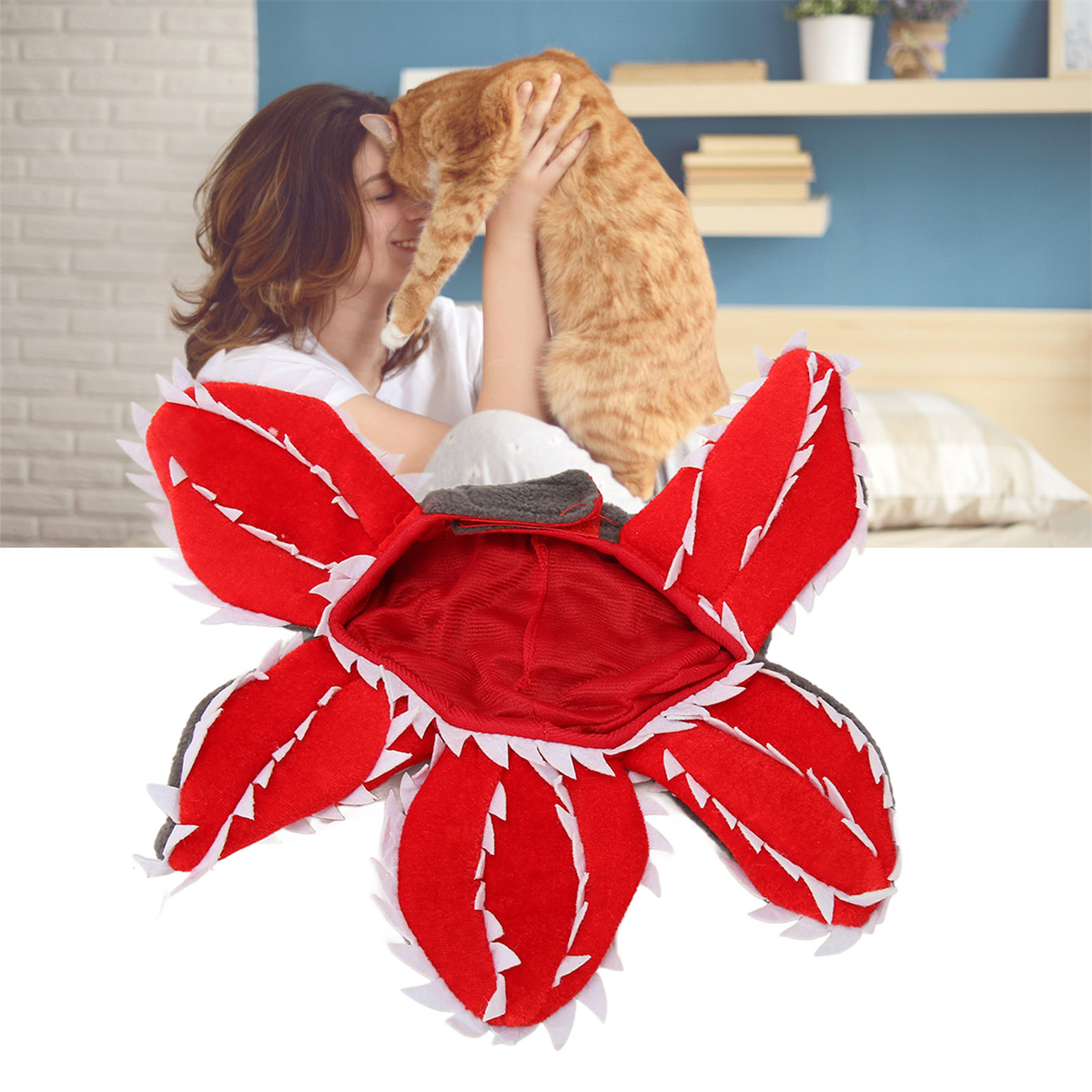 Roter Monsterhut auf einer Katze, die von einer Frau gehalten wird. Weißer Hintergrund.