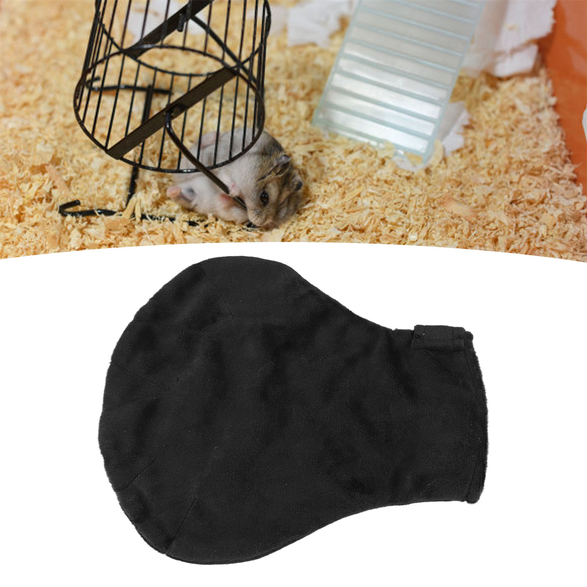 Hamster im Käfig in der Nähe eines schwarzen Tuches. Käfig in einer Ecke mit Holzspänen.