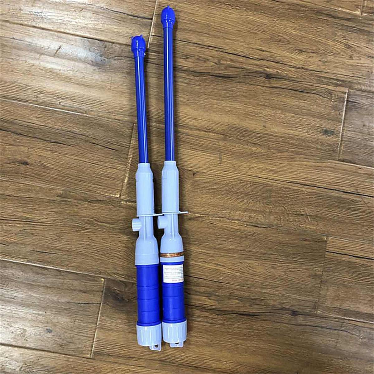 Zwei blaue und weiße elektrische Wasserpumpen auf Holzgrund. Blaue Düsen zeigen nach oben.