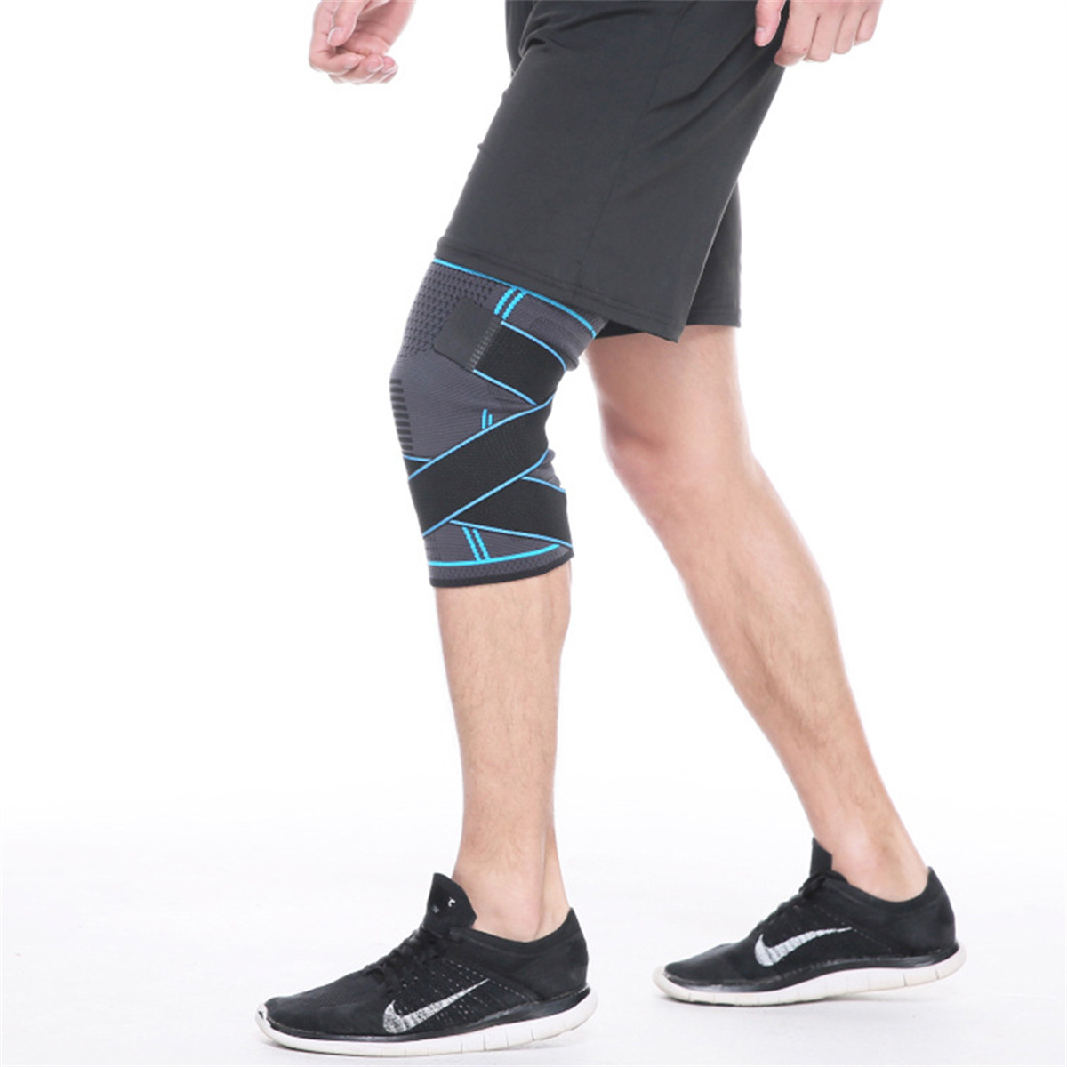 Person trägt Knieorthese, schwarze Shorts und Turnschuhe, weißer Hintergrund.