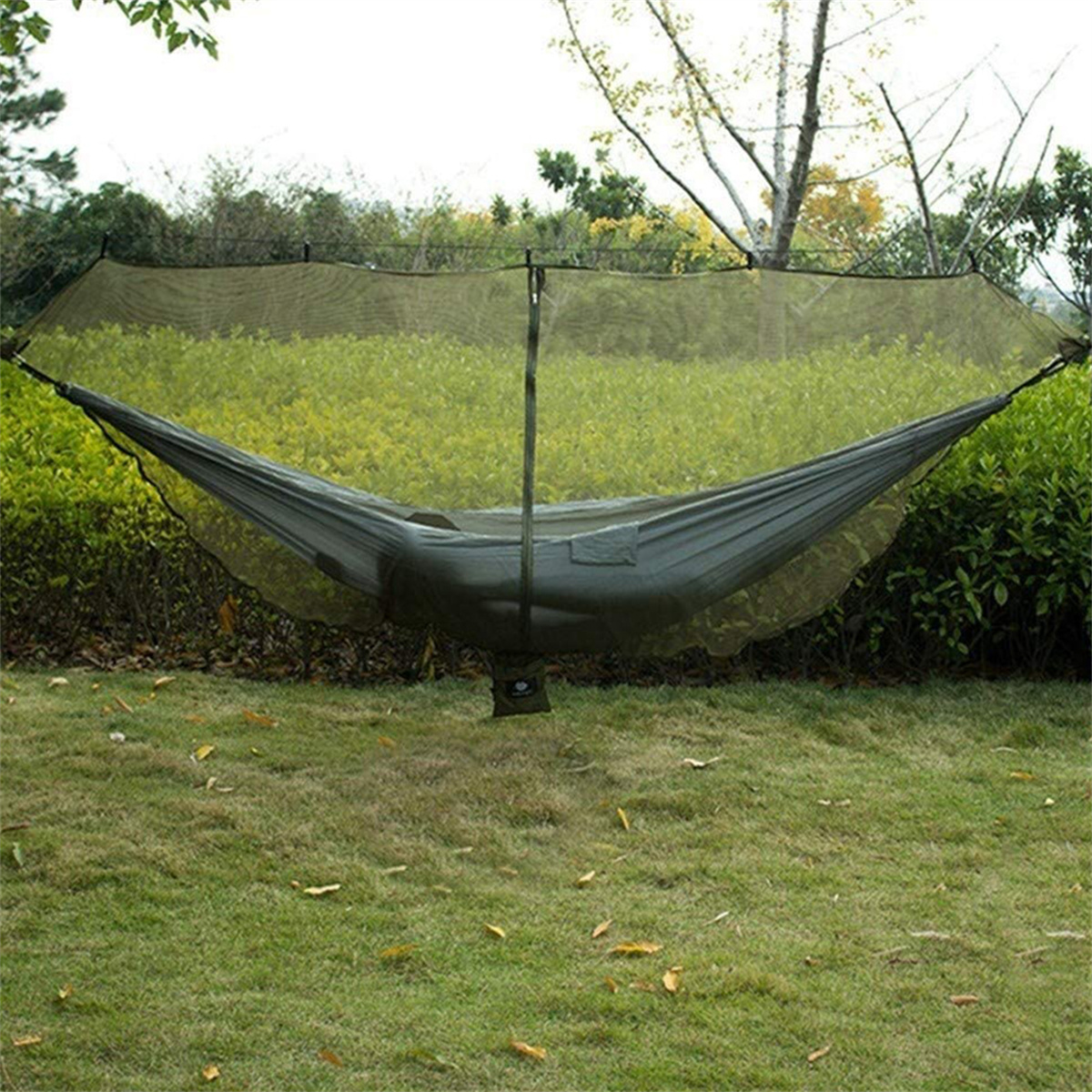 Eine Person ruht in einer grünen Hängematte mit Moskitonetz in einem Grasbereich.