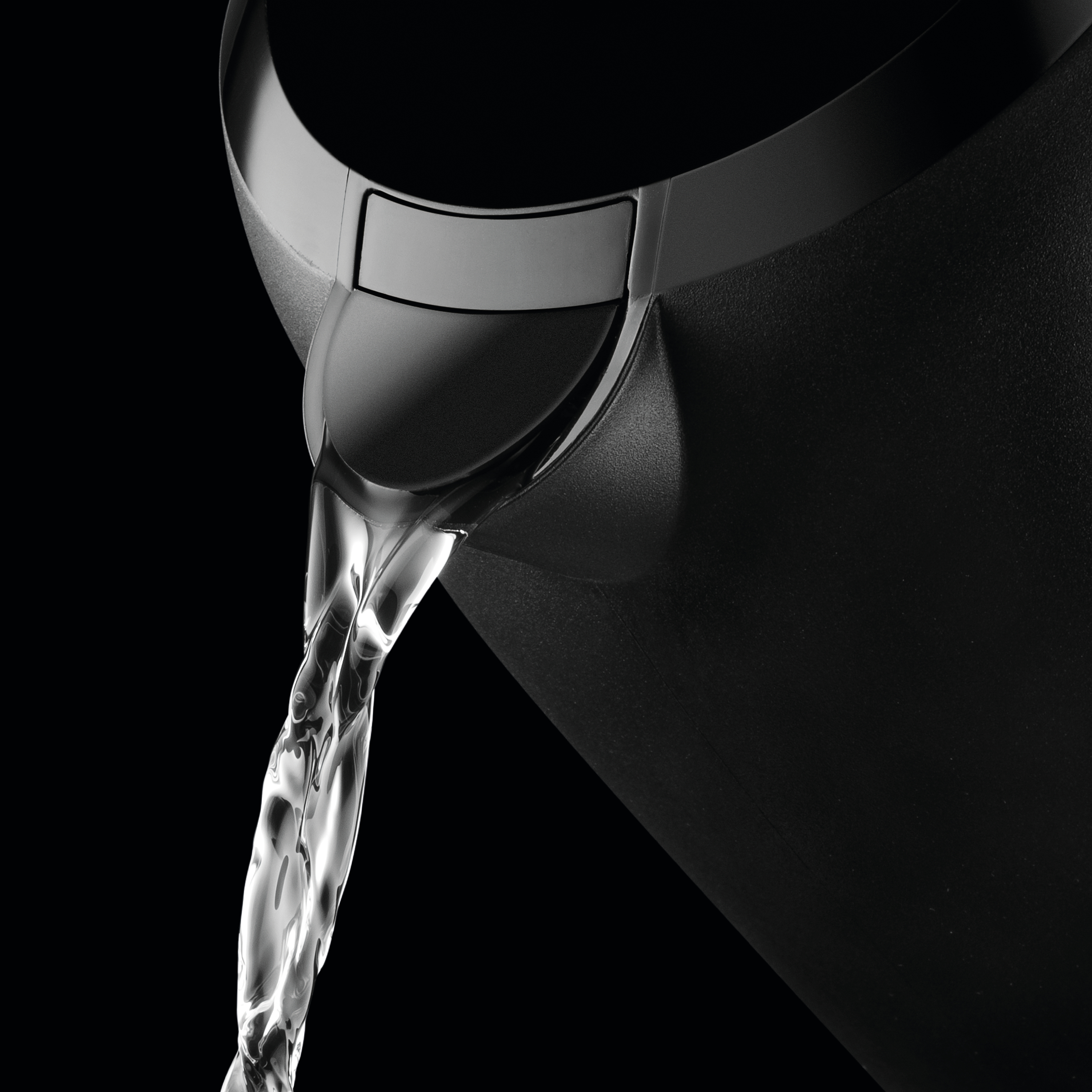 Zbliżenie czarnego wylewu czajnika wylewającego czystą wodę na czarnym tle.