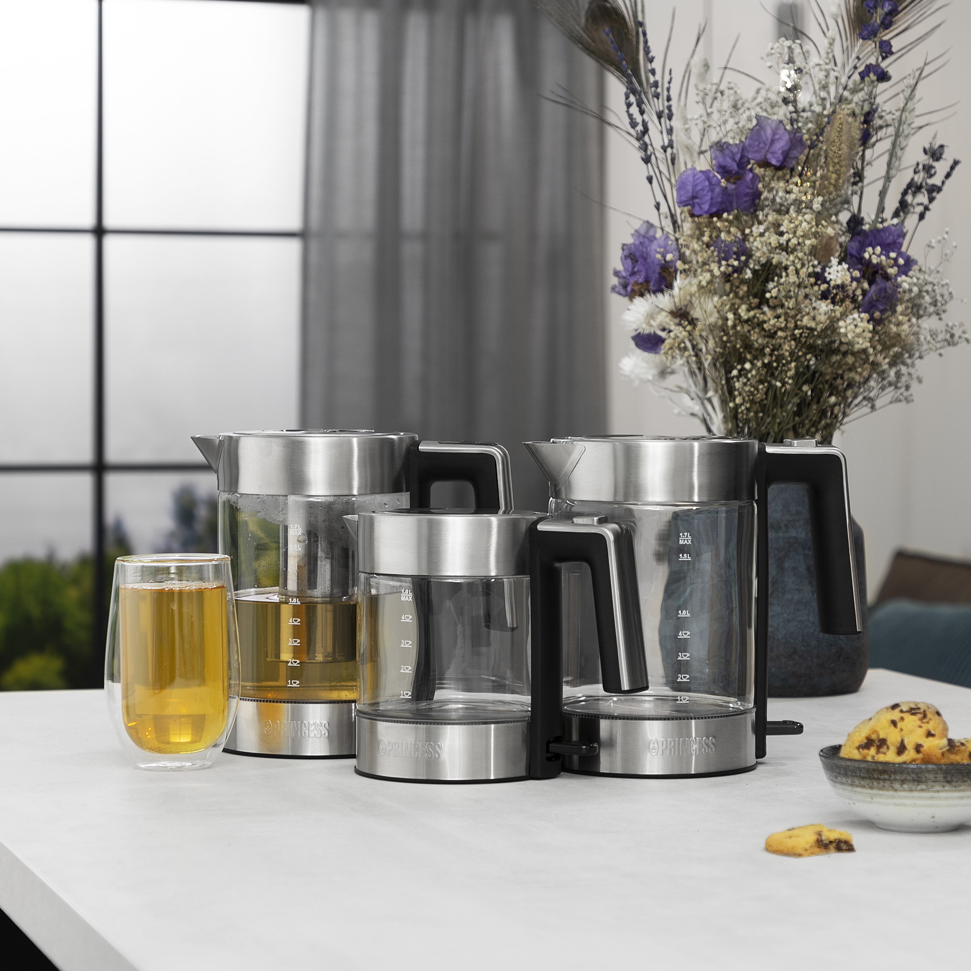 Wiele szklanych czajników i szklanek na białym stole.