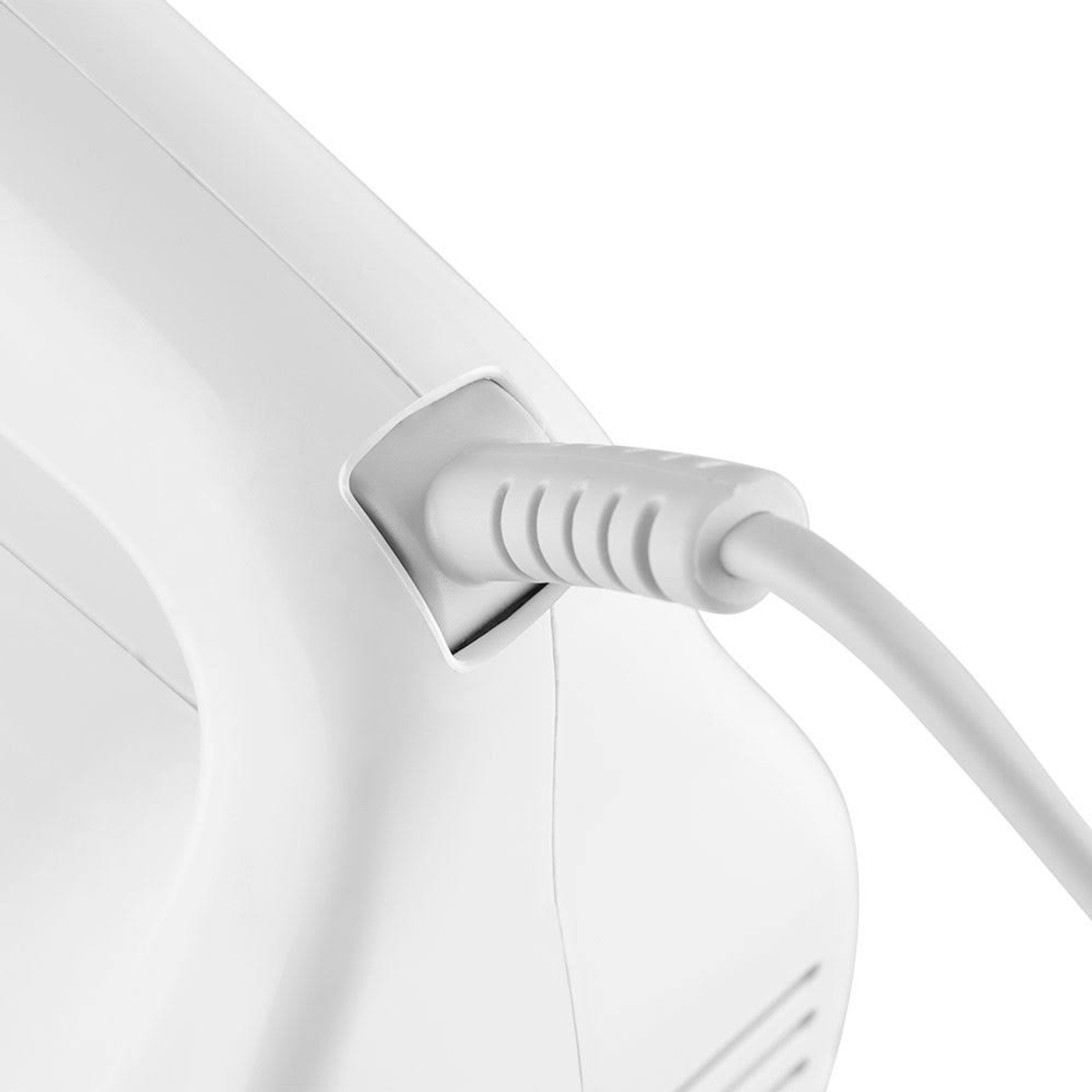 Primer plano de cable eléctrico blanco enchufado a un electrodoméstico blanco.
