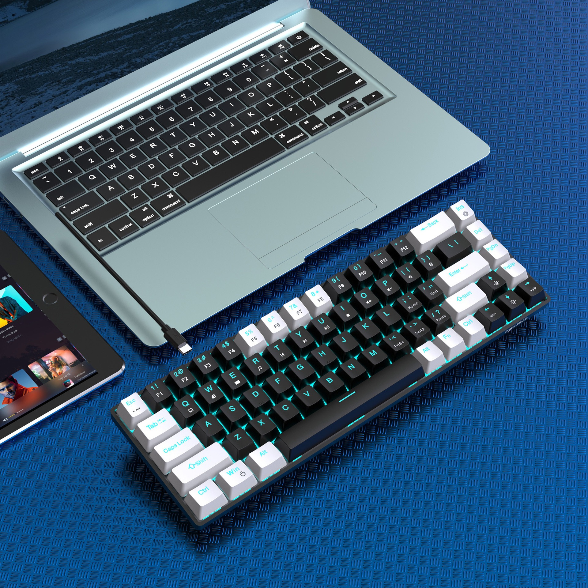 Eine schwarz-weiße Tastatur mit einem Laptop und einem Tablet auf einer blauen Oberfläche.