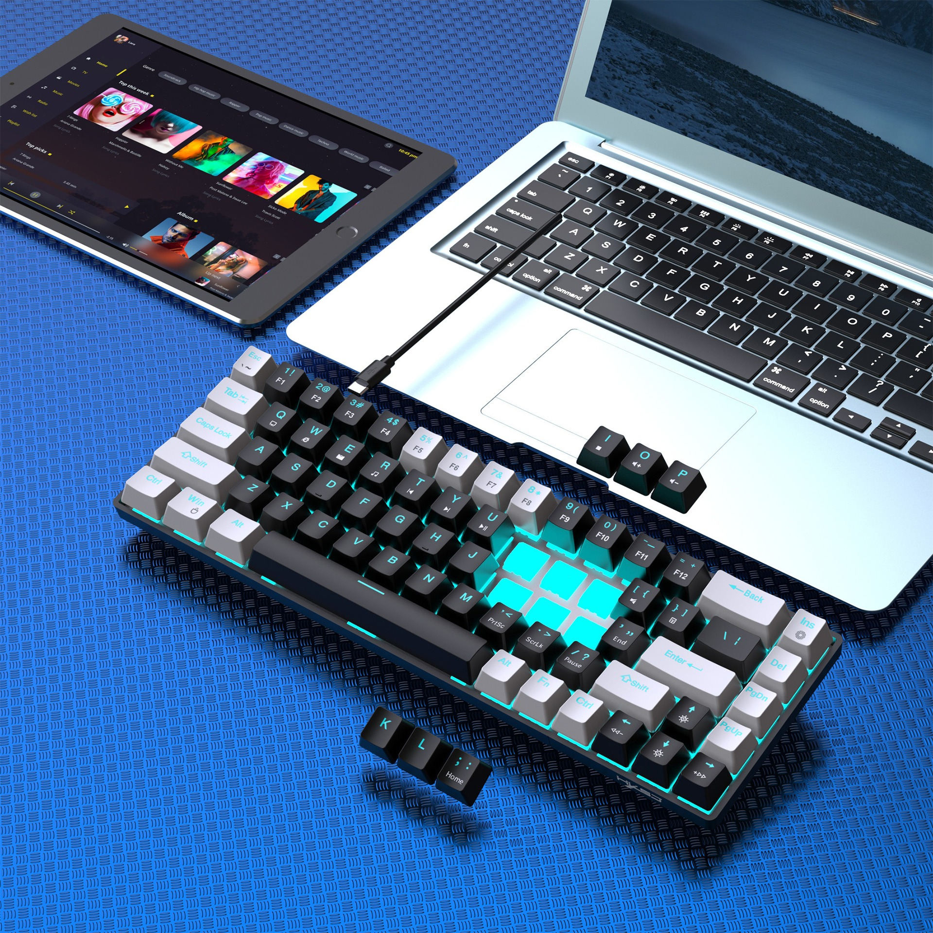 Tastatur mit weißen und schwarzen Tasten, ein Tablet und ein Laptop auf blauem Untergrund.