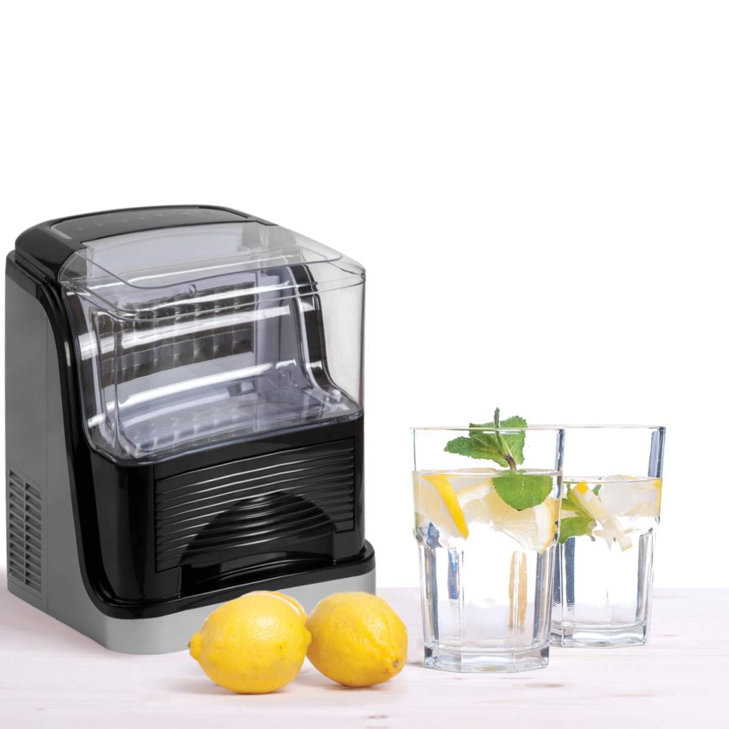 Macchina per il ghiaccio, due limoni e due bicchieri con acqua e menta. Sfondo bianco.