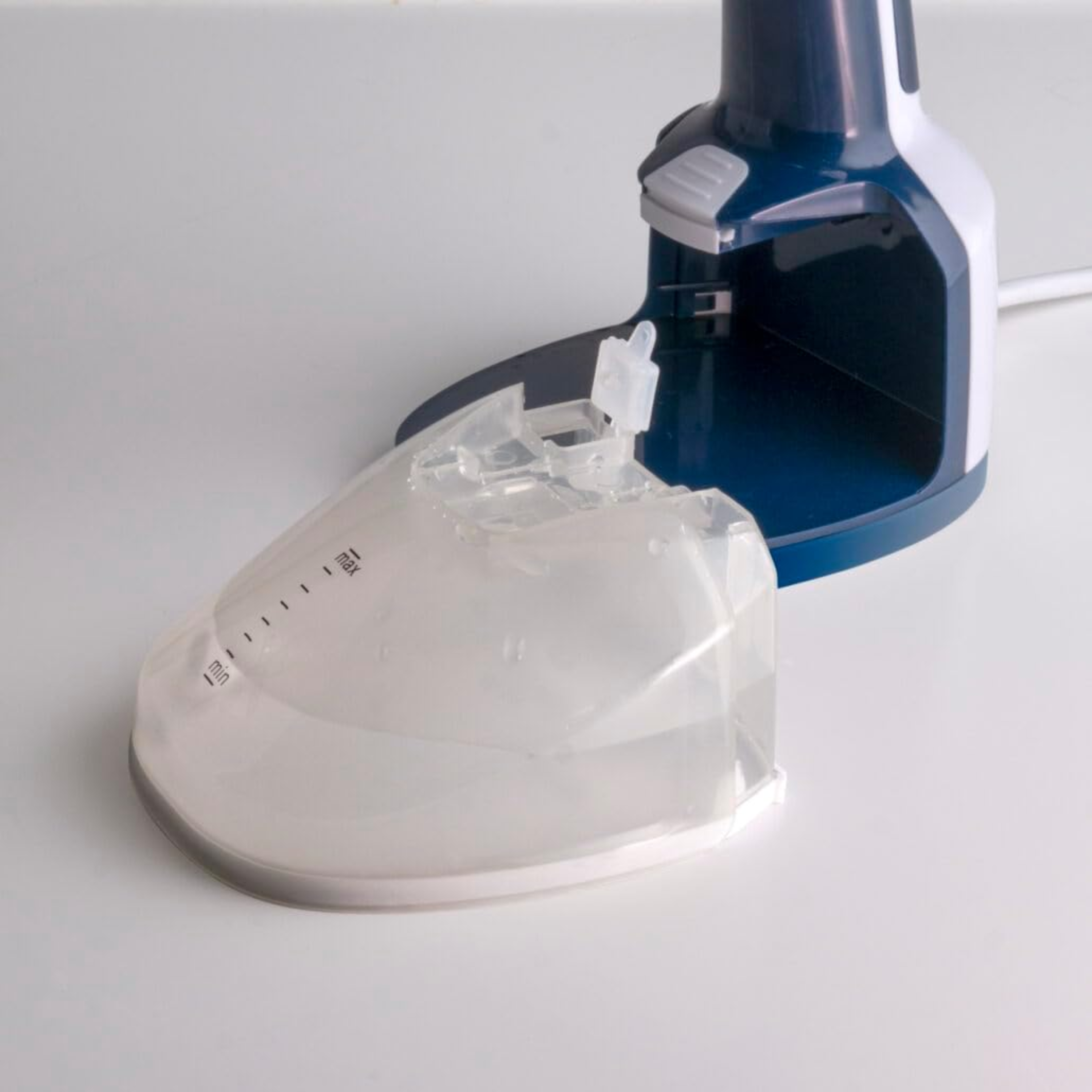 Vaporizzatore per abiti blu e bianco, serbatoio dell'acqua. Sfondo bianco.