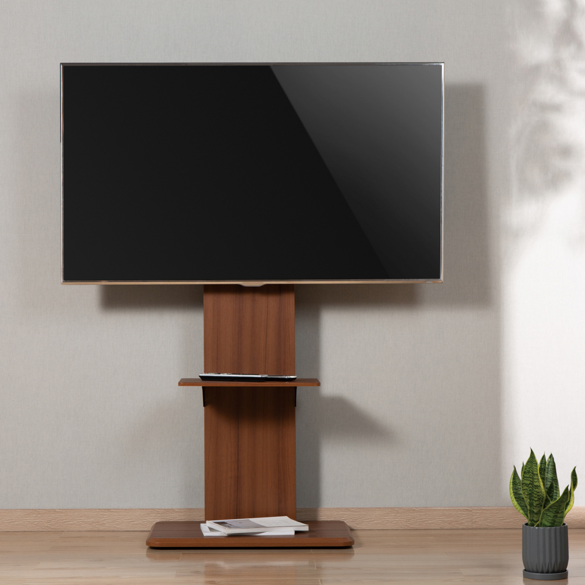 Fernseher auf einem braunen Holzständer mit Regal und Sockel, vor einer Wand mit einer Pflanze rechts.