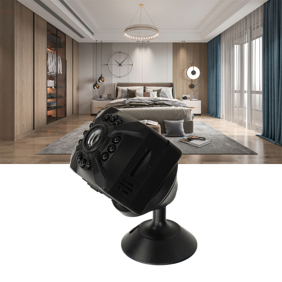 Eine kleine schwarze Kamera auf einem Ständer in einem Raum, mit Bett und Fenstern im Hintergrund.