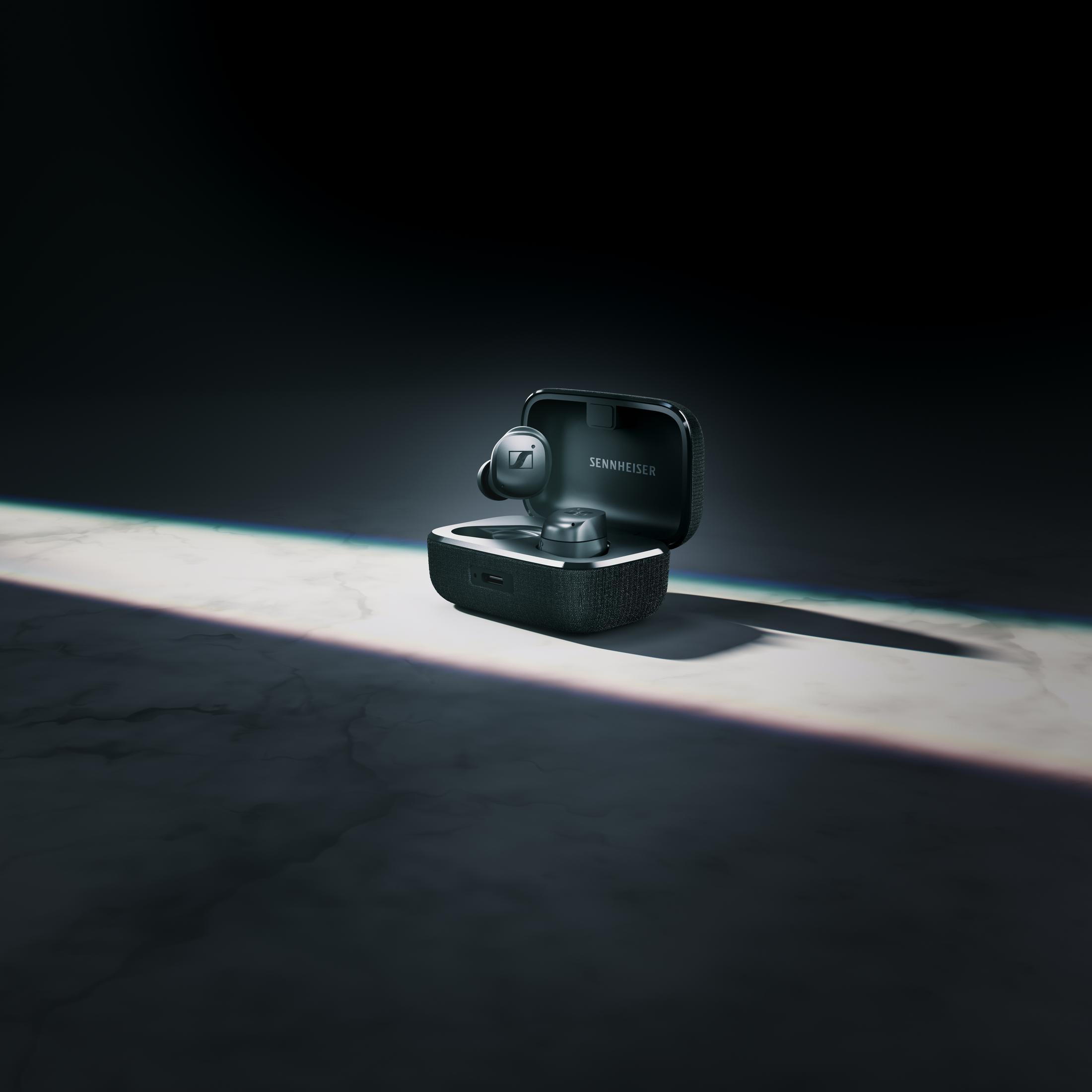 Słuchawki Sennheiser w czarnym etui, na marmurowej powierzchni, oświetlone dramatycznie.