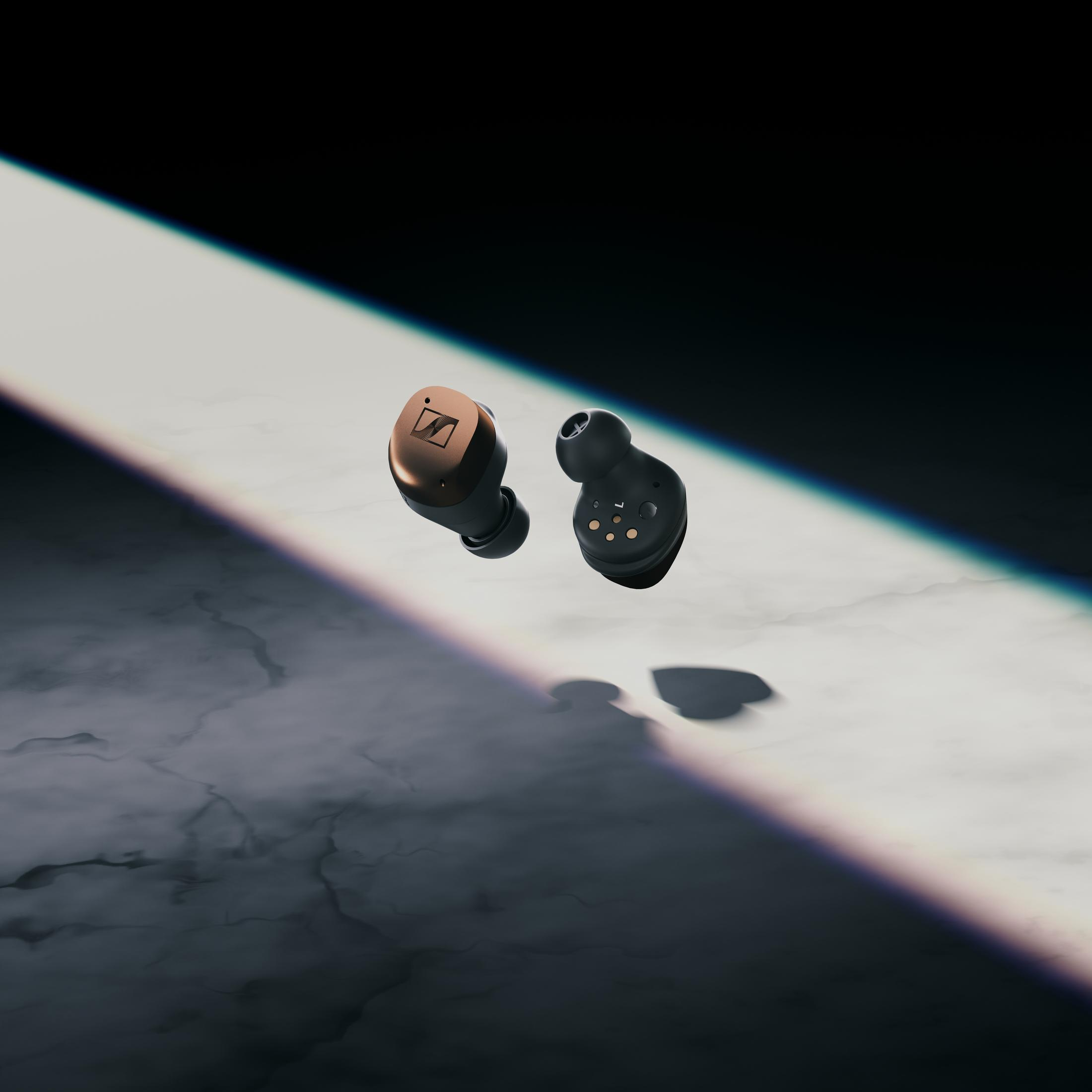 Słuchawki Sennheiser w etui. Słuchawki czarne ze złotymi akcentami. Ciemne tło.