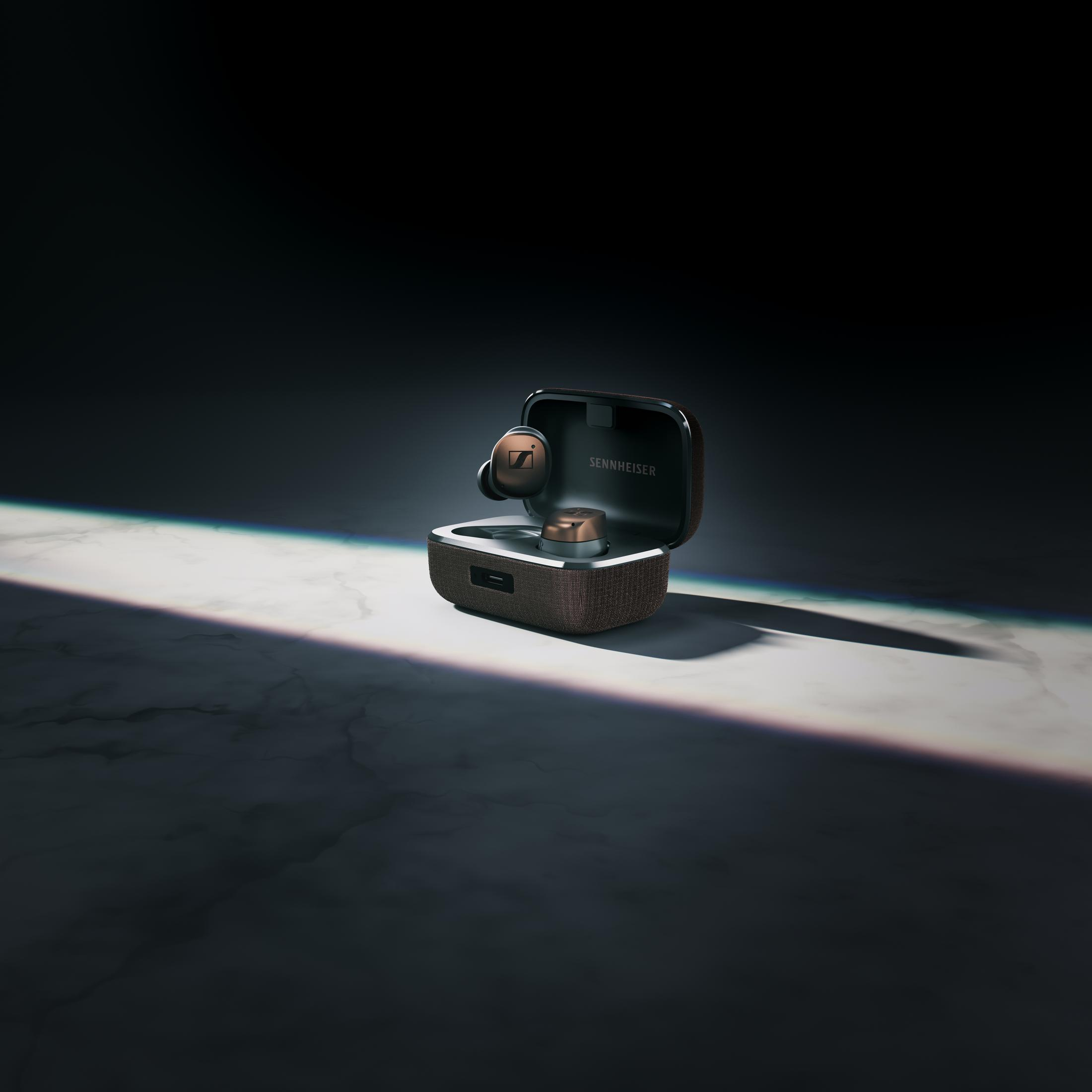 Słuchawki w etui ładującym. Etui otwarte, na marmurowej powierzchni.