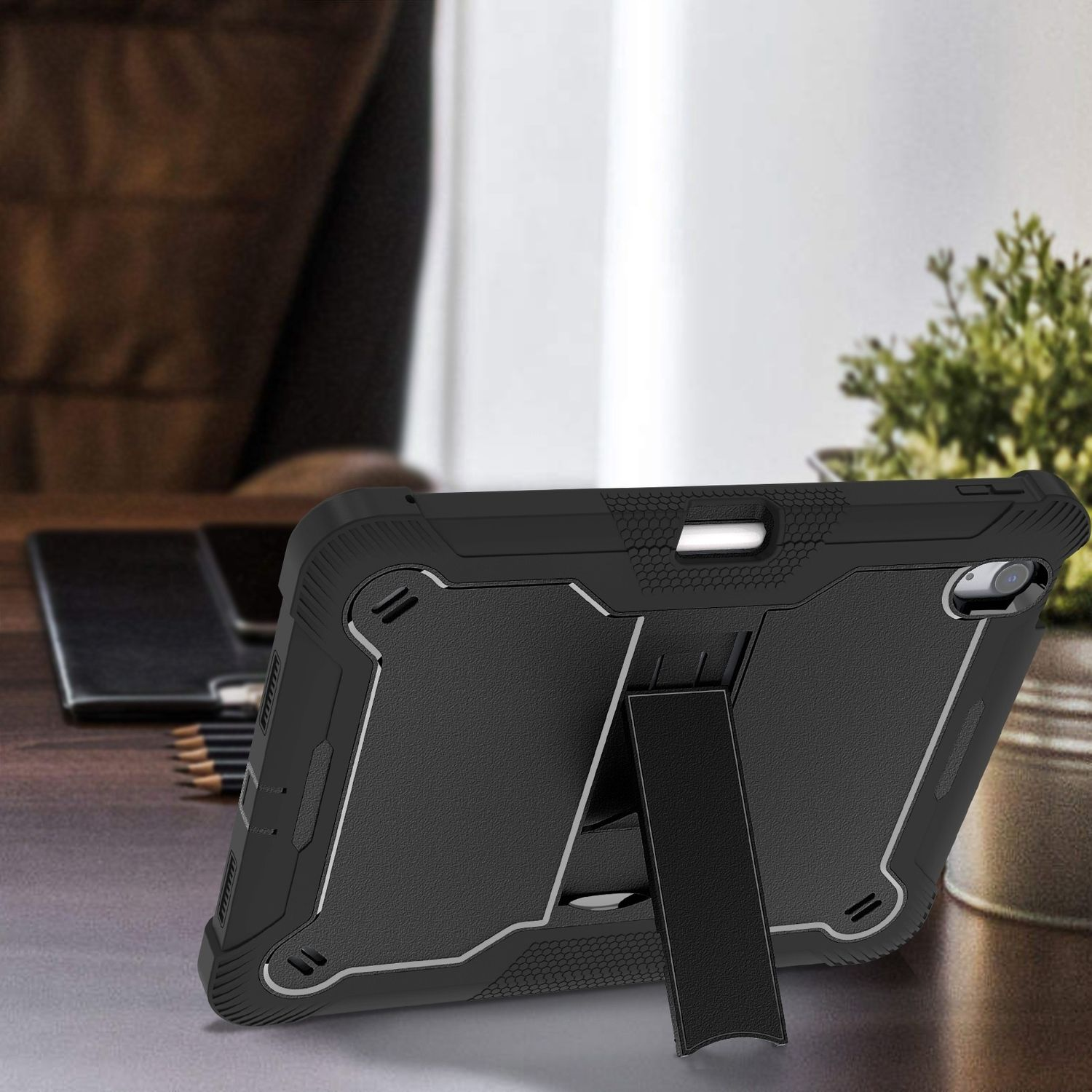 Schwarze Tablet-Hülle mit Ständer auf einem Schreibtisch mit Bleistiften und einer Pflanze.