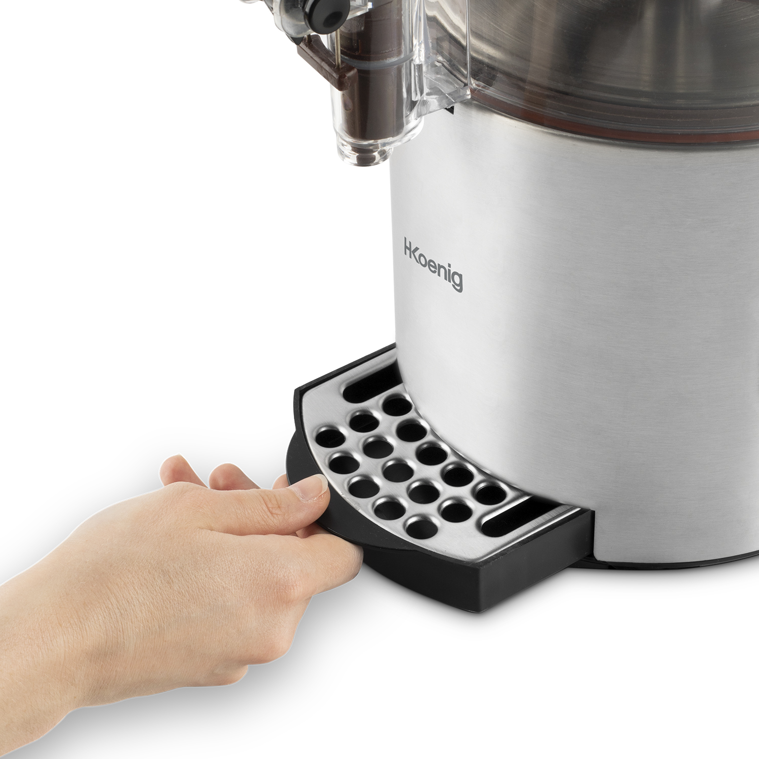 A hand pulls out a black tray from a silver and black espresso machine. HKoenig brand visible.