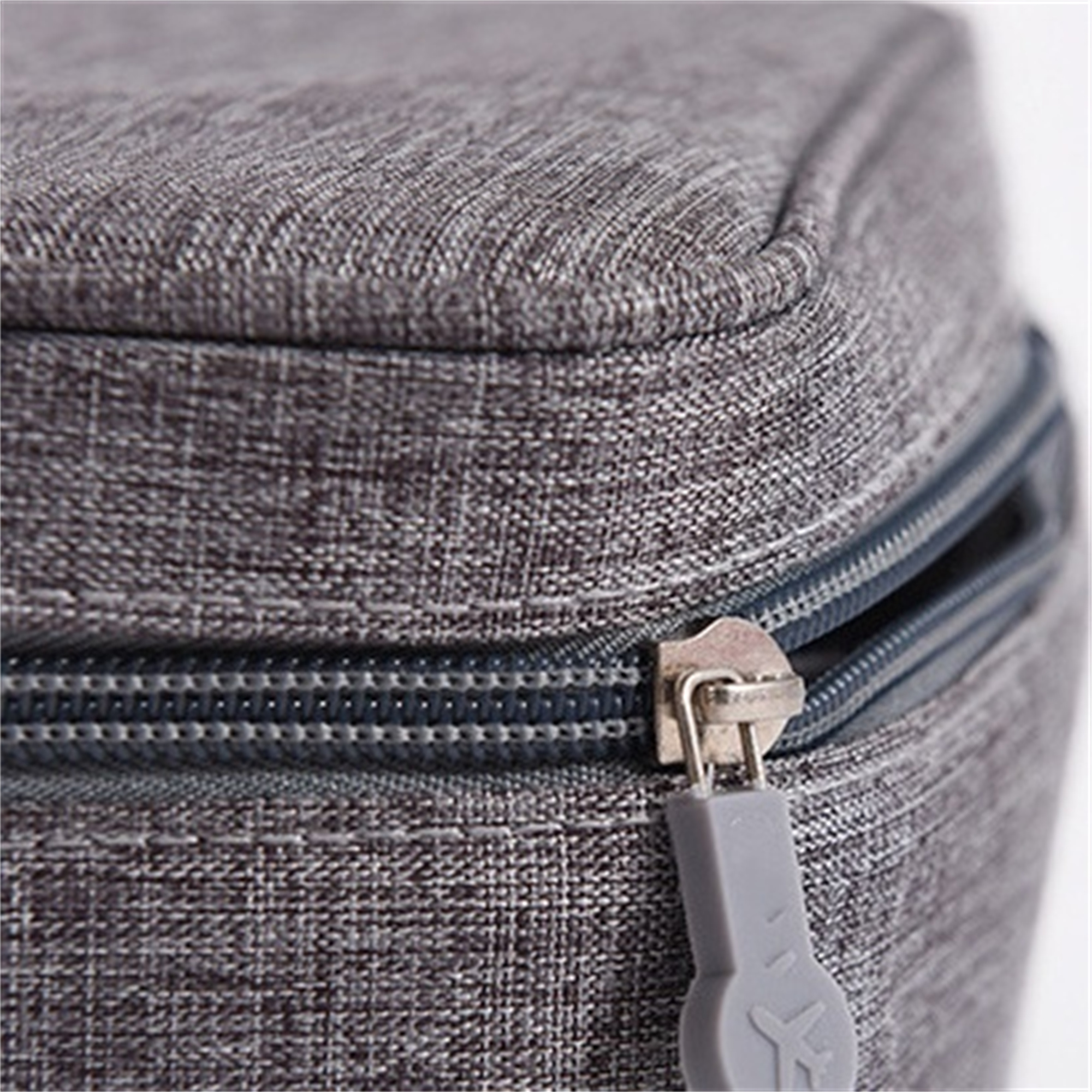 Nahaufnahme einer grauen Stofftasche mit Reißverschluss. Der Reißverschluss ist grau.